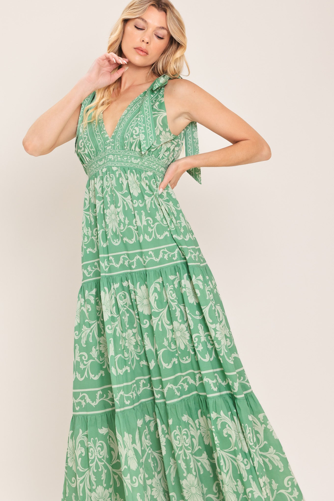 Woman wearing a sage green patterned maxi dress featuring V neckline, shoulder ties, tier skirt and smocked back waistband | Flying Tomato
