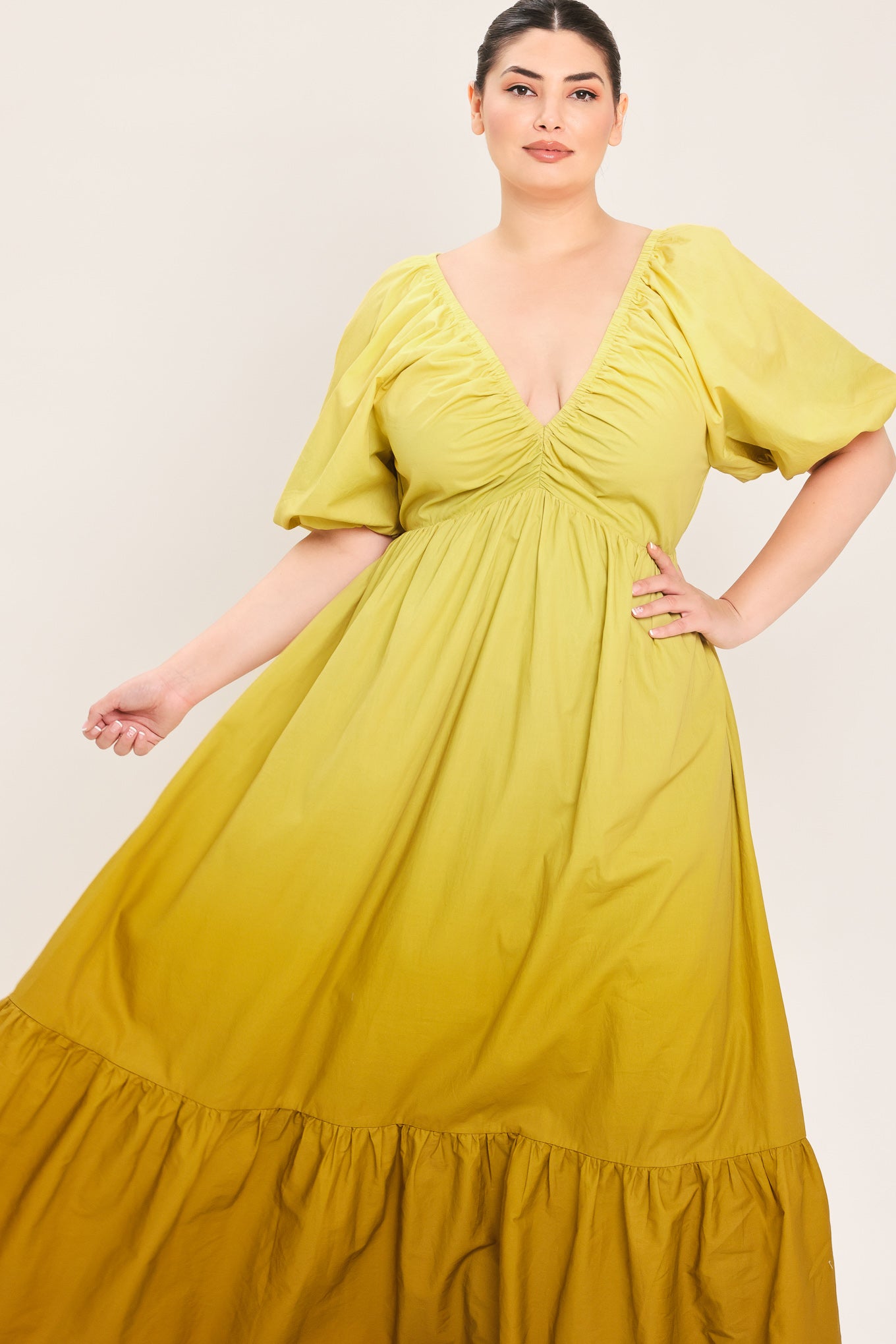 A woman modeling a yellow midi dress with puff sleeves, a deep V-neckline, and a gathered skirt with a tiered hem | Plus Curve Flying Tomato