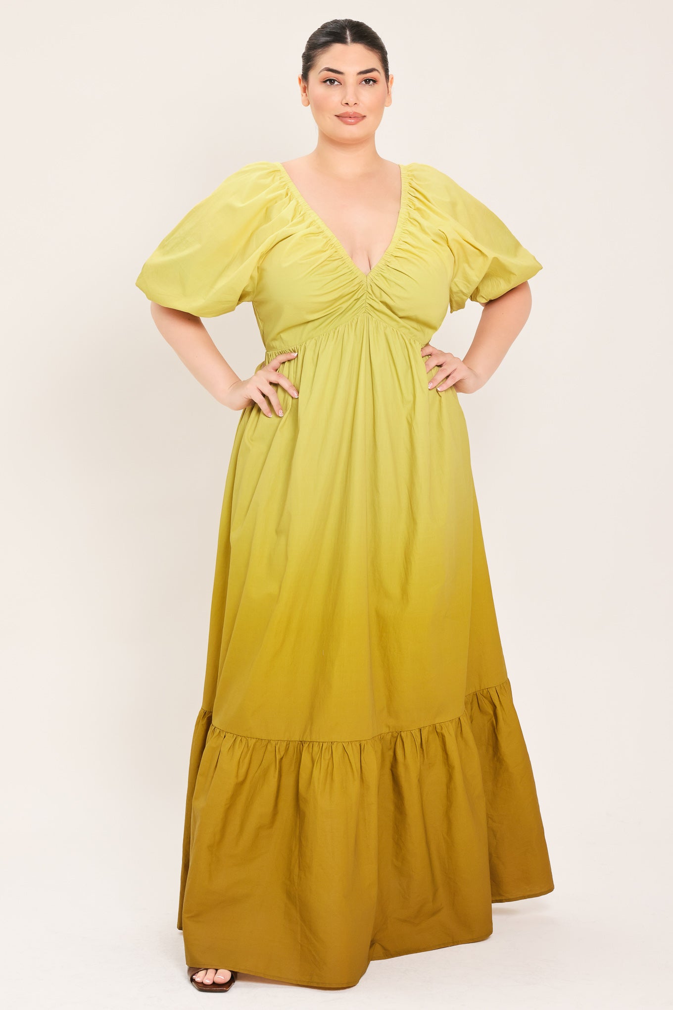 A woman modeling a yellow midi dress with puff sleeves, a deep V-neckline, and a gathered skirt with a tiered hem | Plus Curve Flying Tomato
