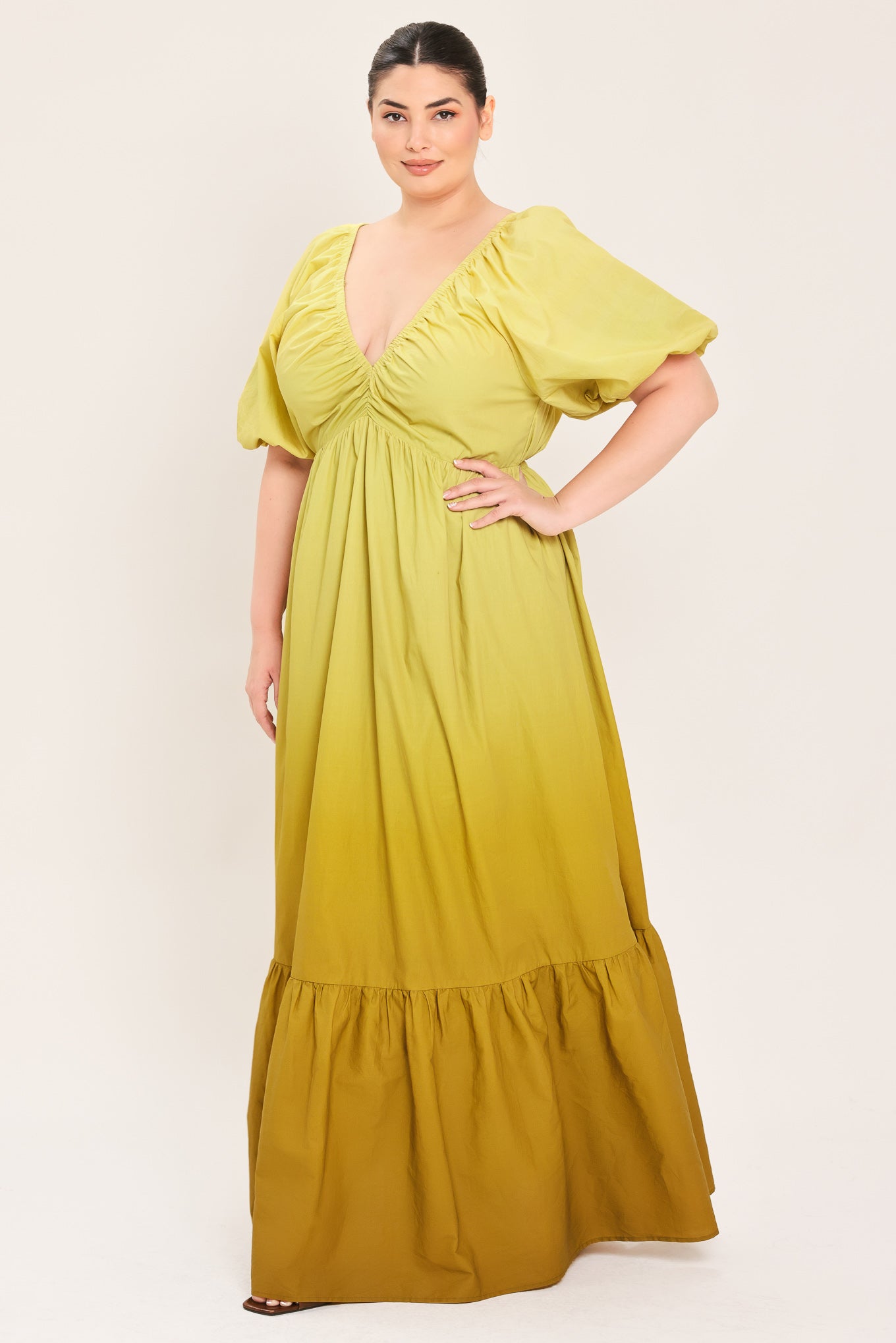 A woman modeling a yellow midi dress with puff sleeves, a deep V-neckline, and a gathered skirt with a tiered hem | Plus Curve Flying Tomato