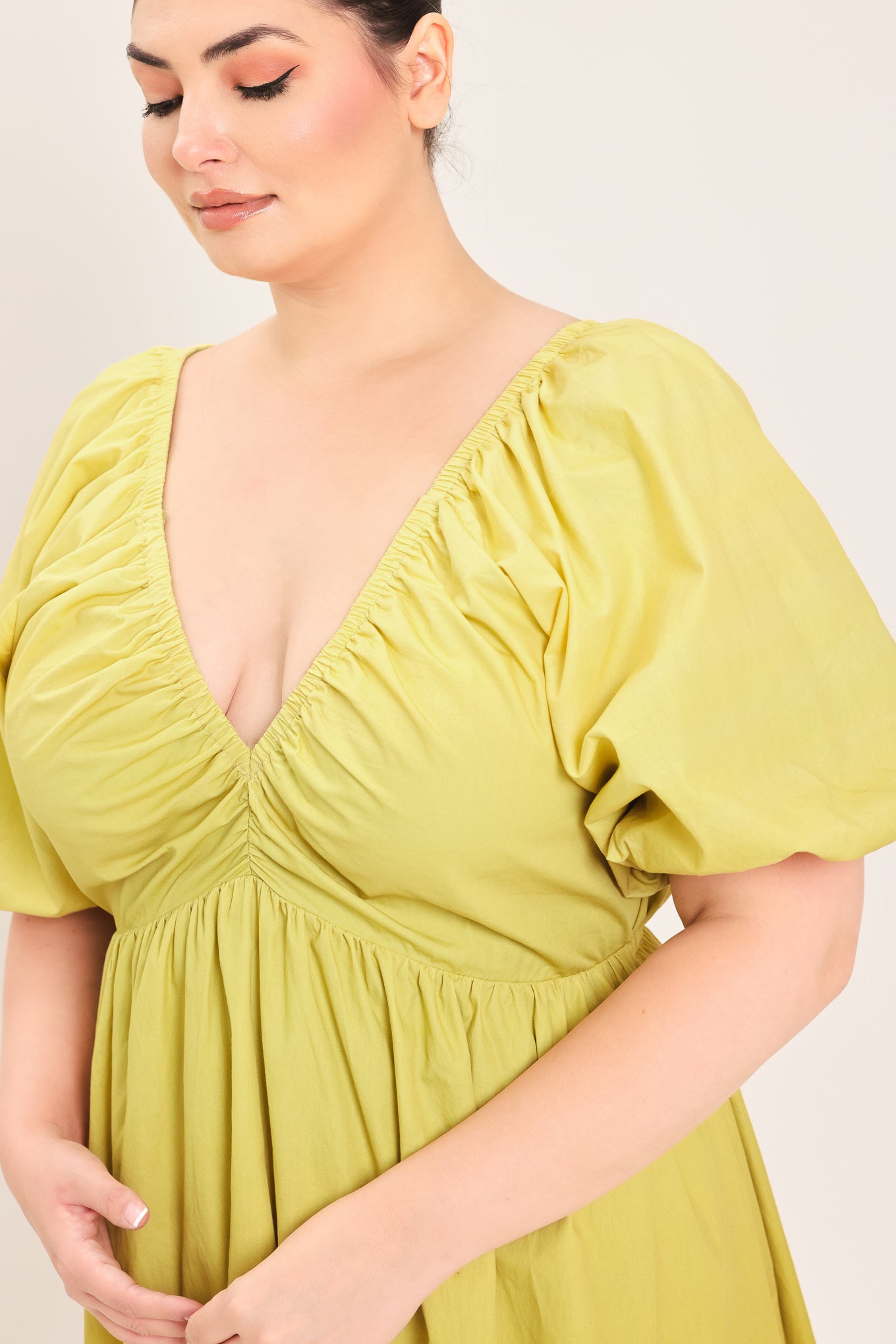 A woman modeling a yellow midi dress with puff sleeves, a deep V-neckline, and a gathered skirt with a tiered hem | Plus Curve Flying Tomato