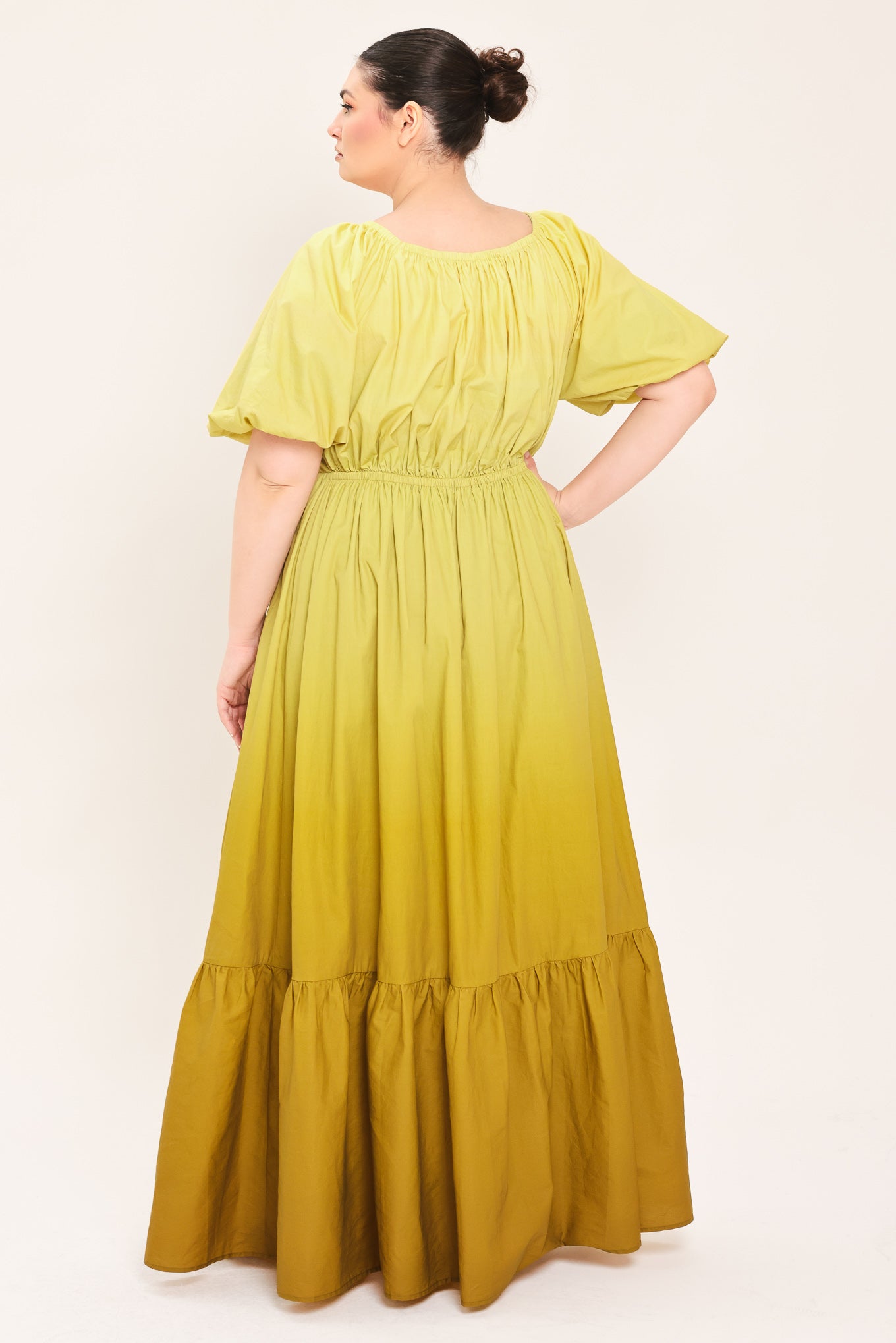 A woman modeling a yellow midi dress with puff sleeves, a deep V-neckline, and a gathered skirt with a tiered hem | Plus Curve Flying Tomato