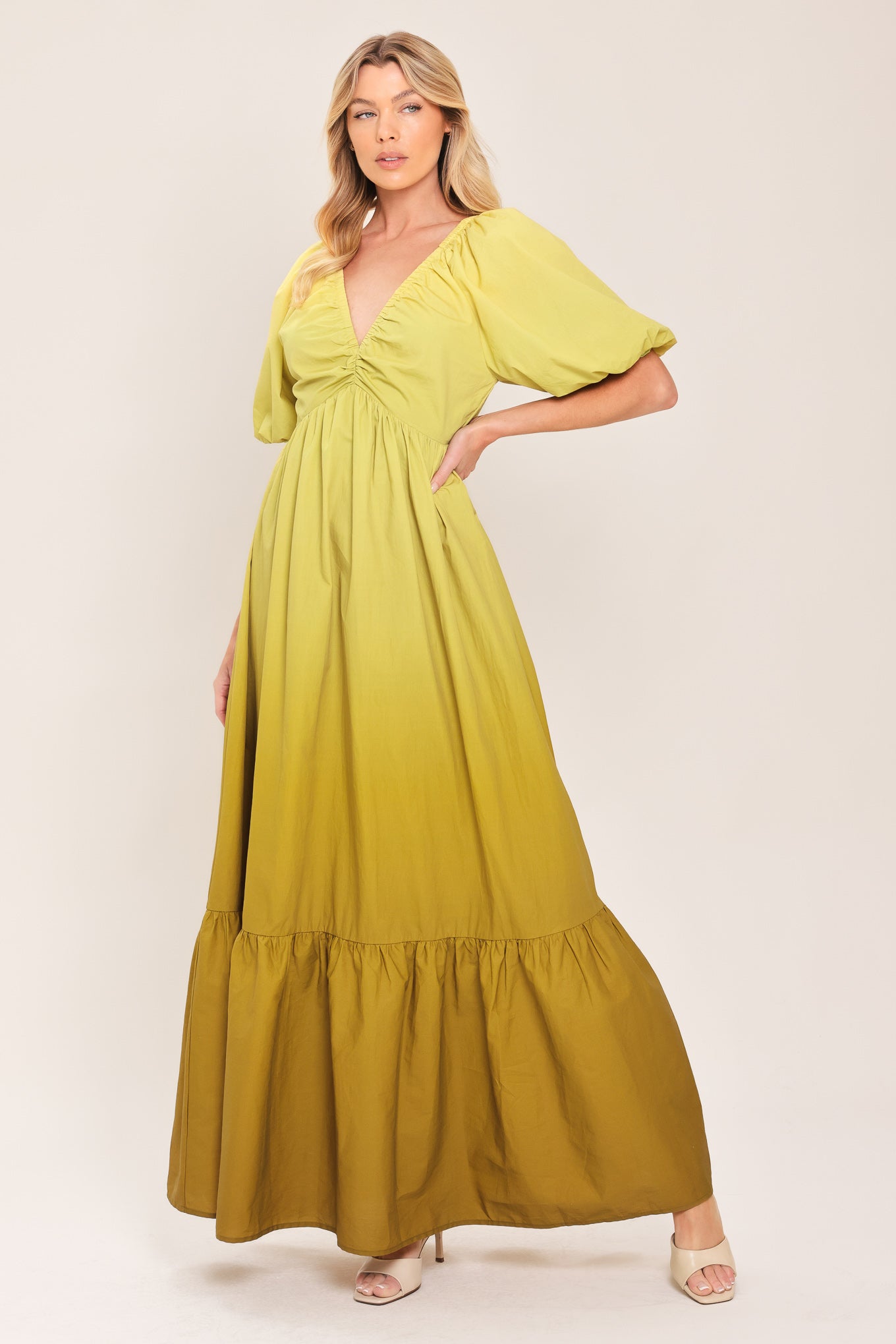 A woman wearing a yellow-green maxi dress with puff sleeves, a gathered V-neckline, and a tiered ruffle hem | Flying Tomato