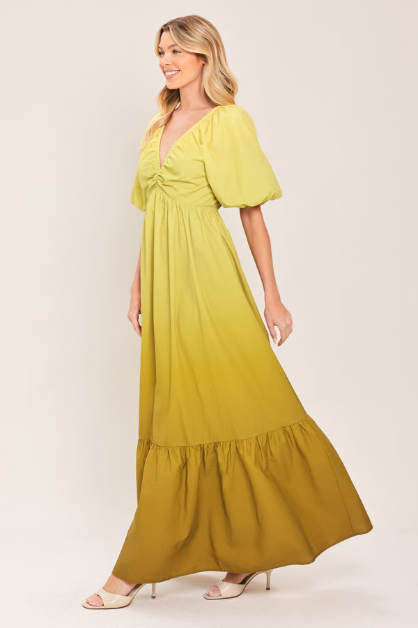 A woman wearing a yellow-green maxi dress with puff sleeves, a gathered V-neckline, and a tiered ruffle hem | Flying Tomato