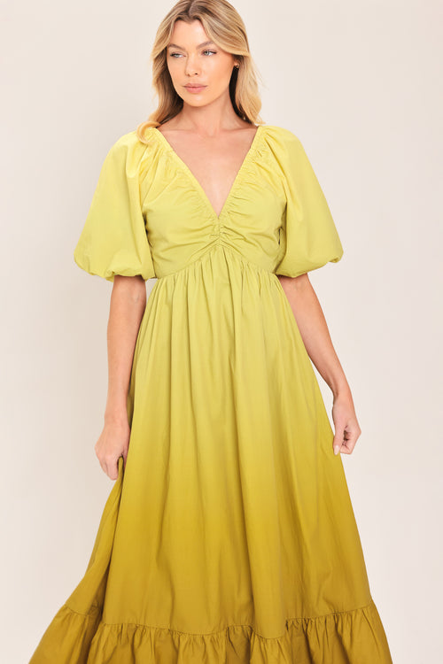 A woman wearing a yellow-green maxi dress with puff sleeves, a gathered V-neckline, and a tiered ruffle hem | Flying Tomato