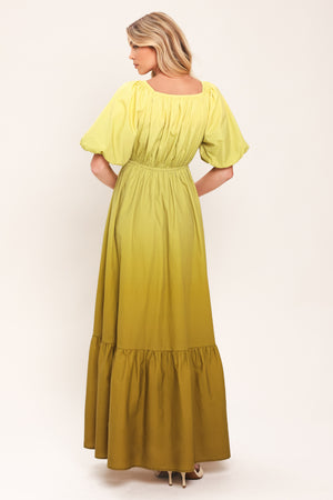 A woman wearing a yellow-green maxi dress with puff sleeves, a gathered V-neckline, and a tiered ruffle hem | Flying Tomato