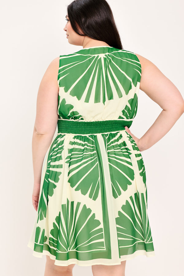 Woman wearing a sleeveless ivory with green leaf pattern mini dress featuring V neckline, full skirt and smocked back waistband | Flying Tomato