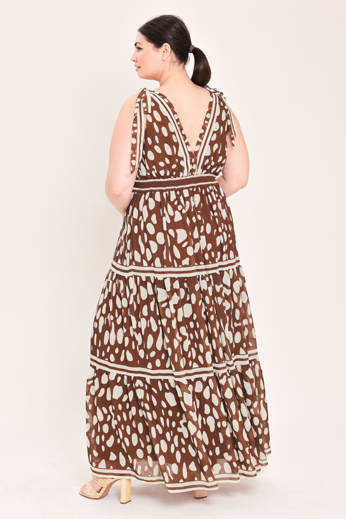 Woman wearing a brown and white patterned dress on a white background