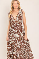 Woman wearing a brown and white spot patterned maxi dress featuring V neckline, shoulder ties, tier skirt and smocked back waistband | Flying Tomato