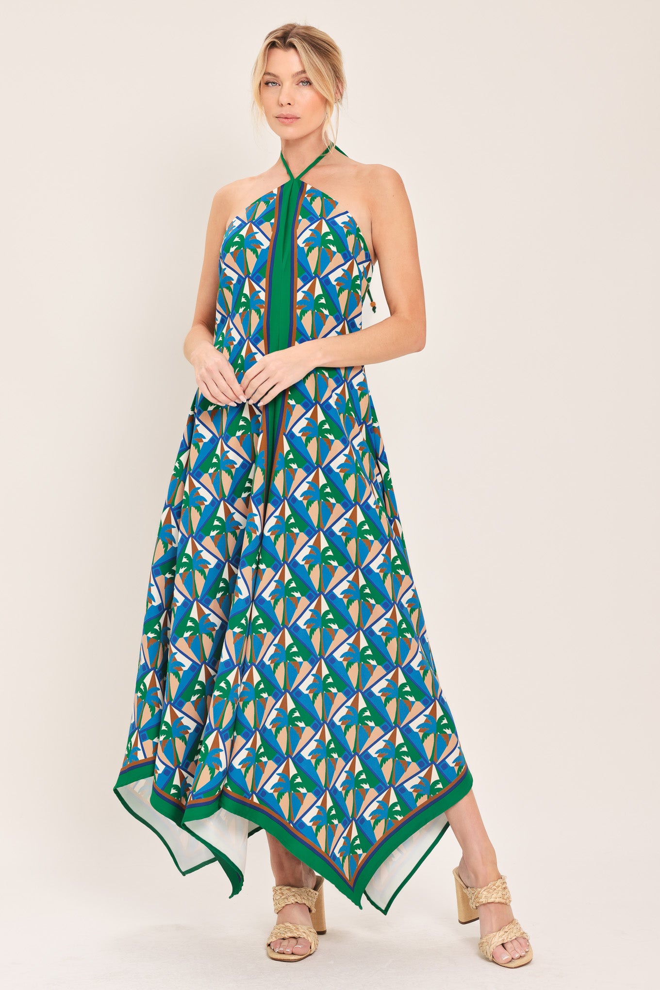 Woman wearing a colorful geometric patterned midi dress featuring halter neckline with tie, hanky hem and back zipper closure | Flying Tomato