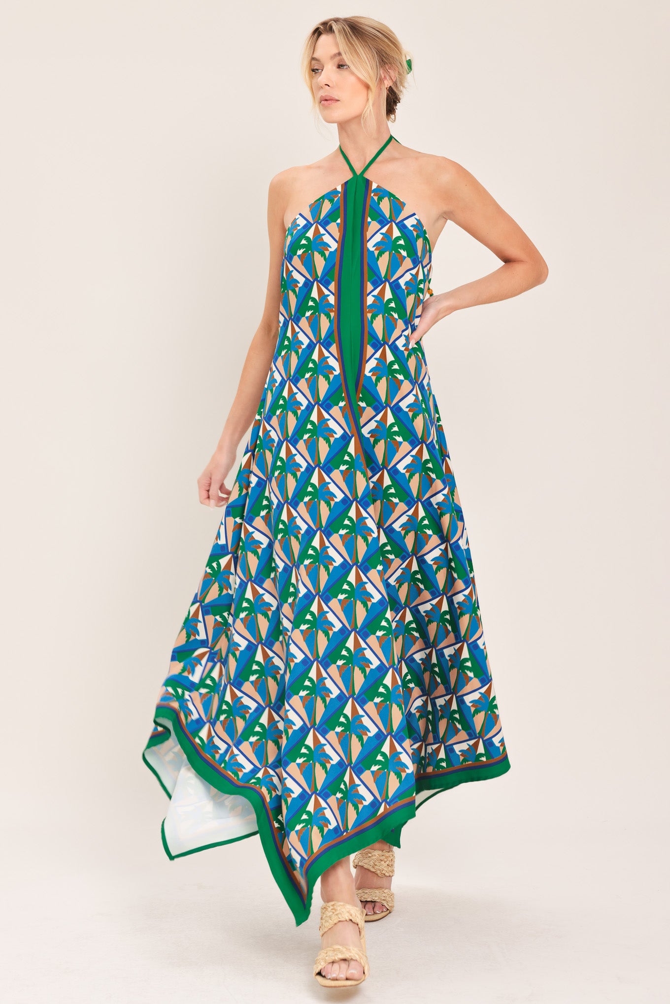Woman wearing a colorful geometric patterned midi dress featuring halter neckline with tie, hanky hem and back zipper closure | Flying Tomato