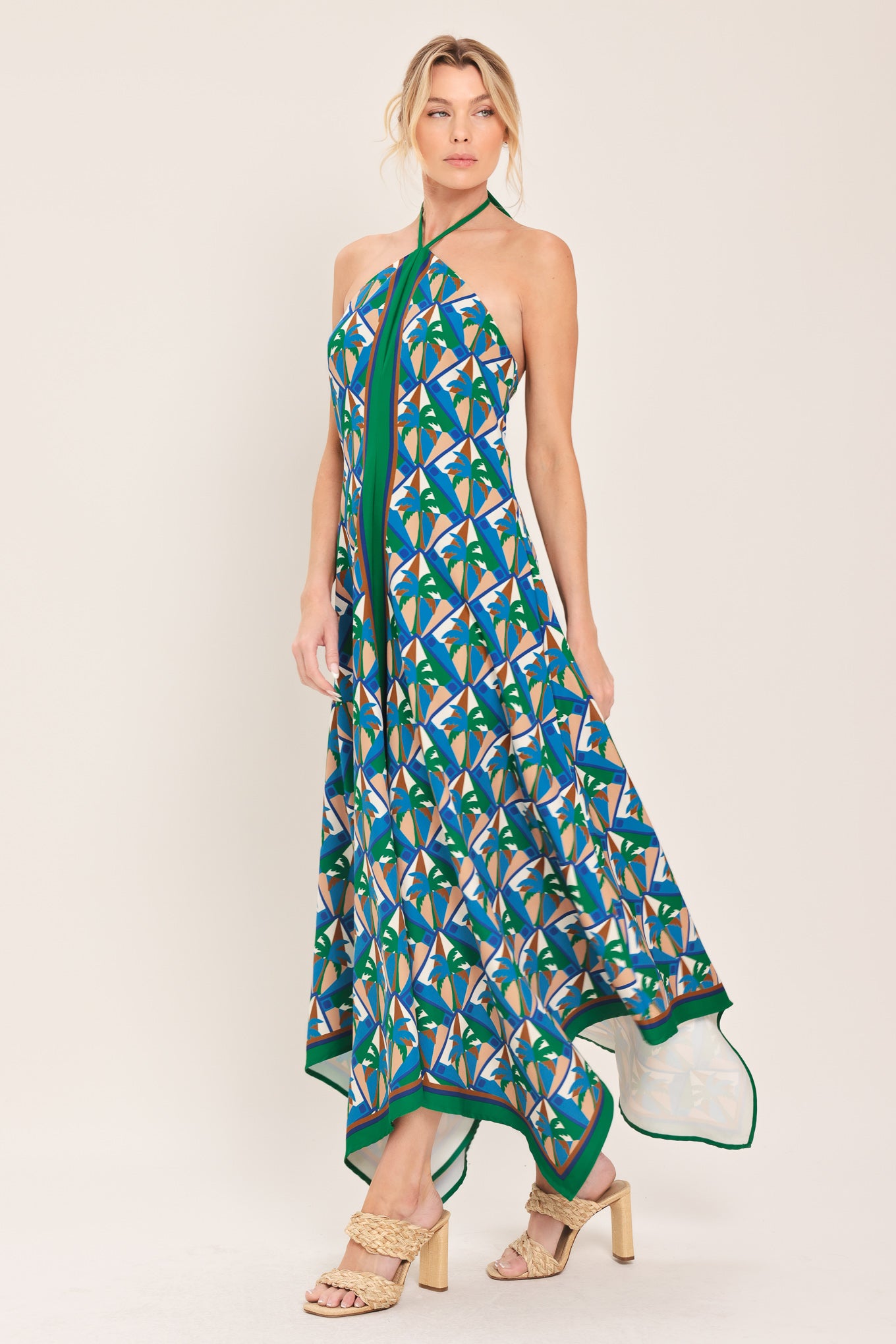 Woman wearing a colorful geometric patterned midi dress featuring halter neckline with tie, hanky hem and back zipper closure | Flying Tomato