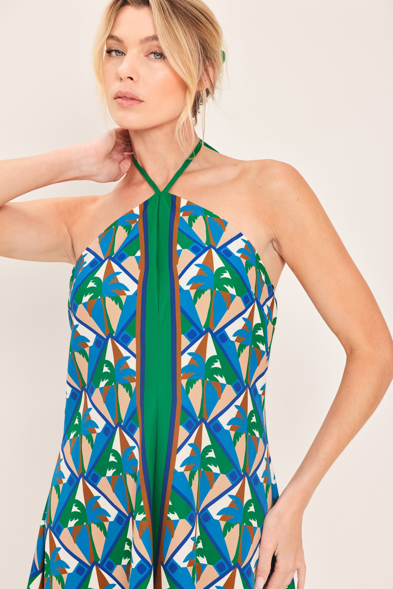 Woman wearing a colorful geometric patterned midi dress featuring halter neckline with tie, hanky hem and back zipper closure | Flying Tomato