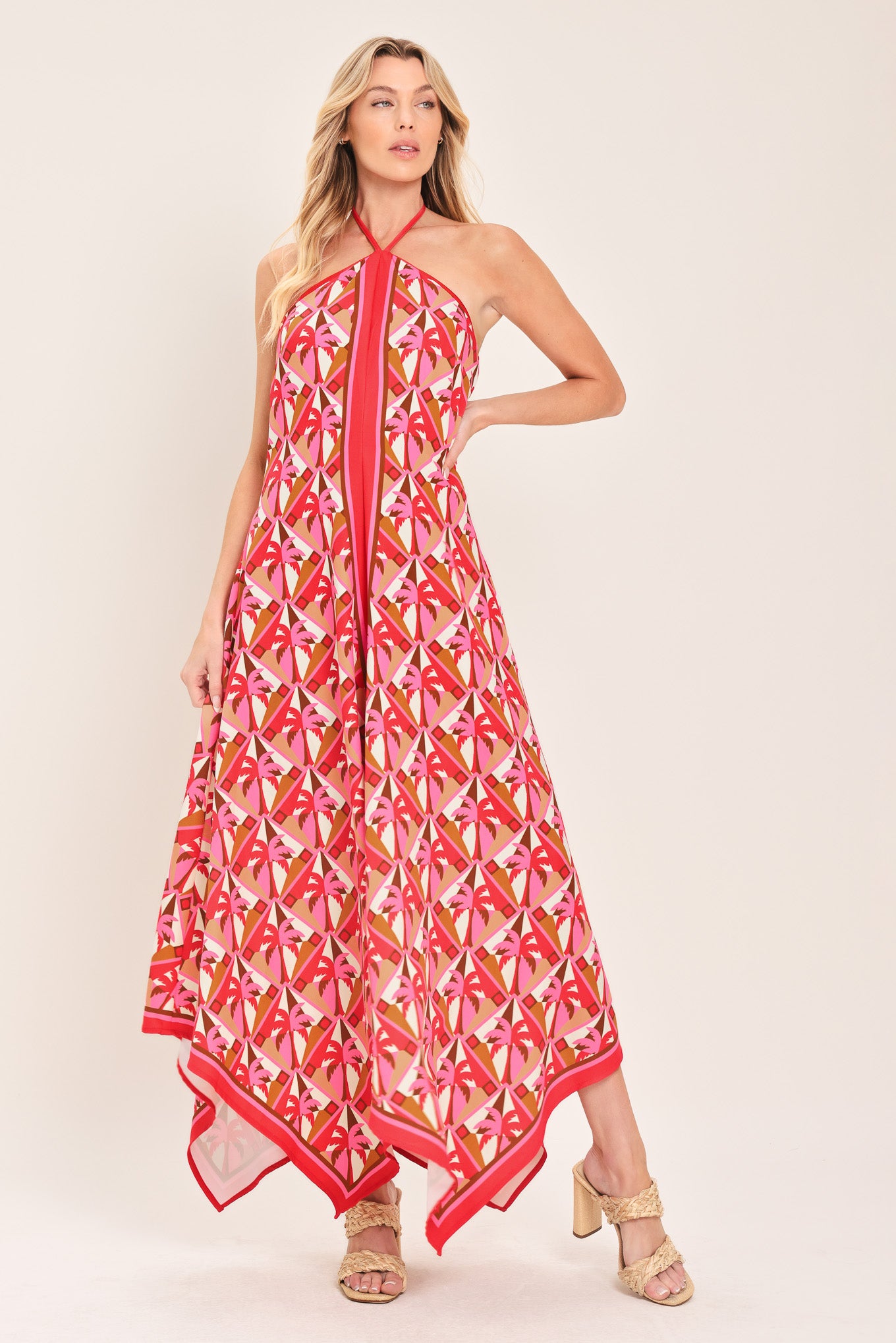 Woman wearing a colorful geometric patterned midi dress featuring halter neckline with tie, hanky hem and back zipper closure | Flying Tomato