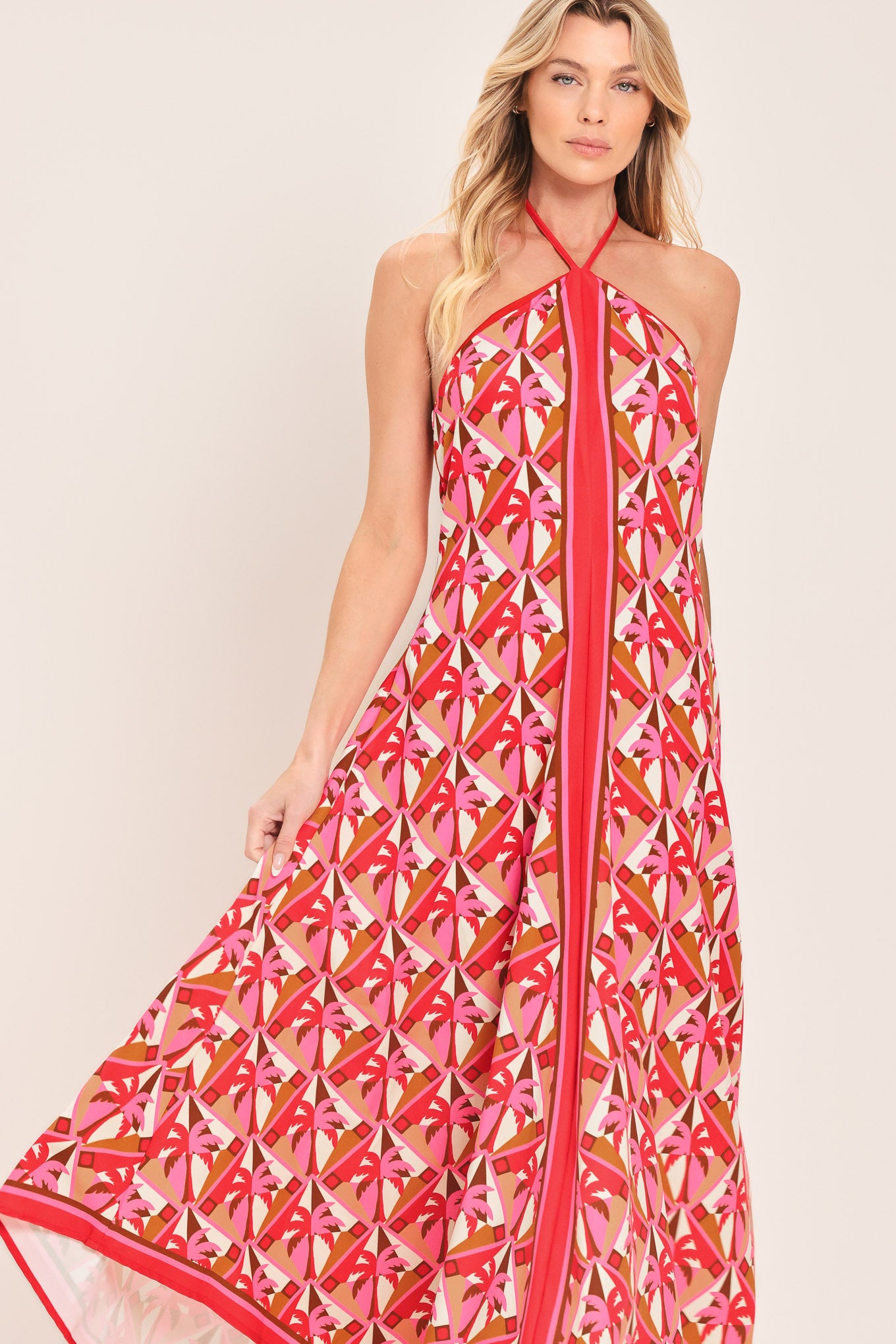 Woman wearing a colorful geometric patterned midi dress featuring halter neckline with tie, hanky hem and back zipper closure | Flying Tomato