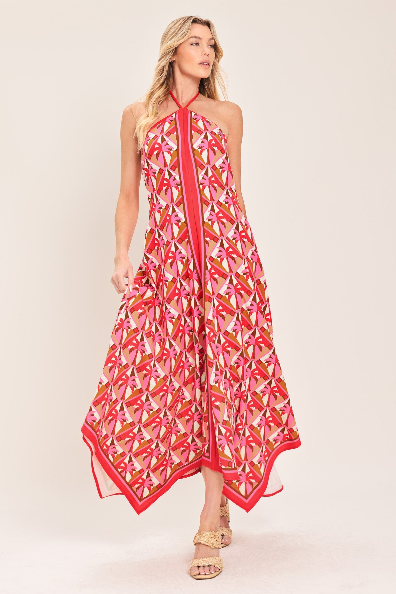 Woman wearing a colorful geometric patterned midi dress featuring halter neckline with tie, hanky hem and back zipper closure | Flying Tomato