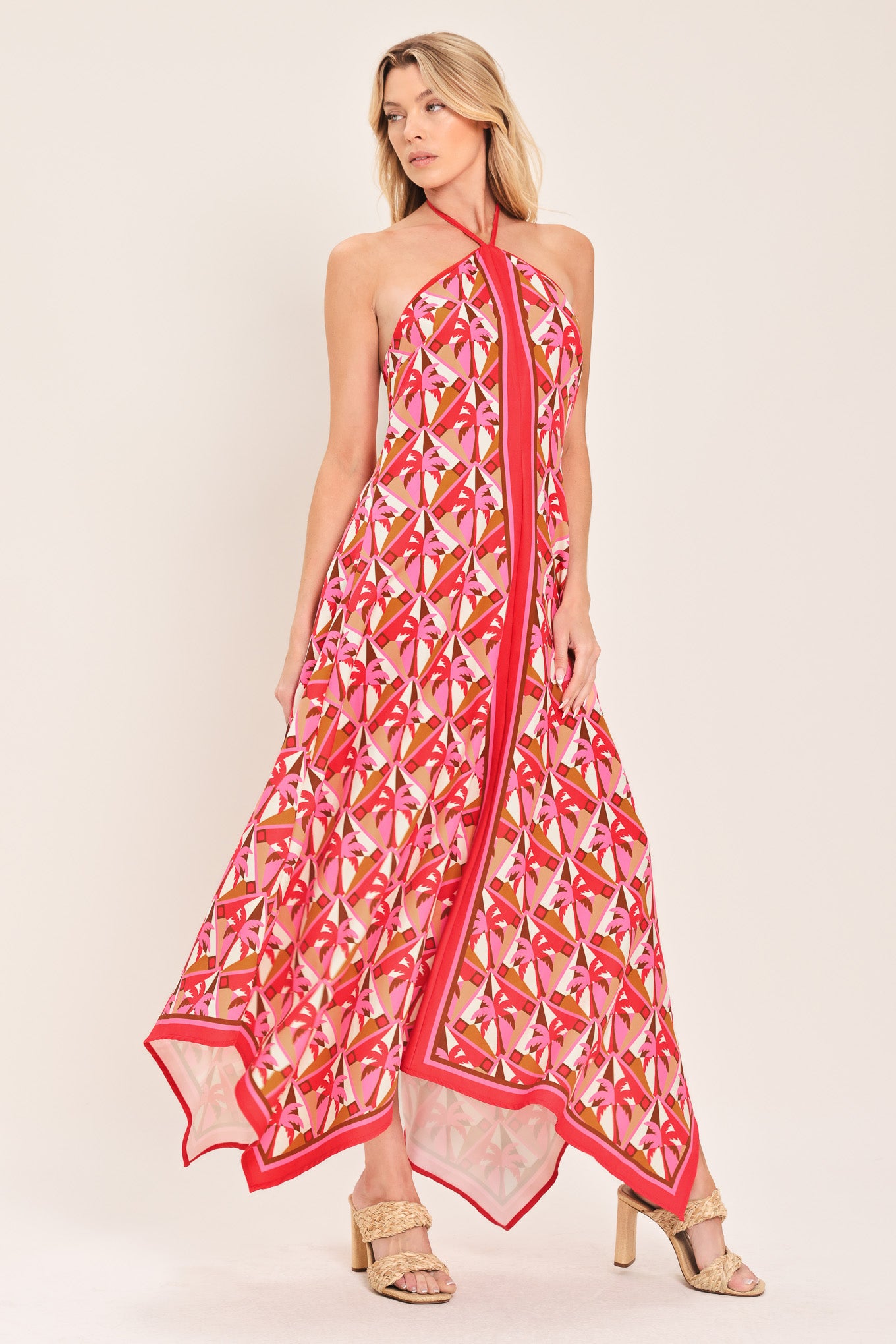 Woman wearing a colorful geometric patterned midi dress featuring halter neckline with tie, hanky hem and back zipper closure | Flying Tomato