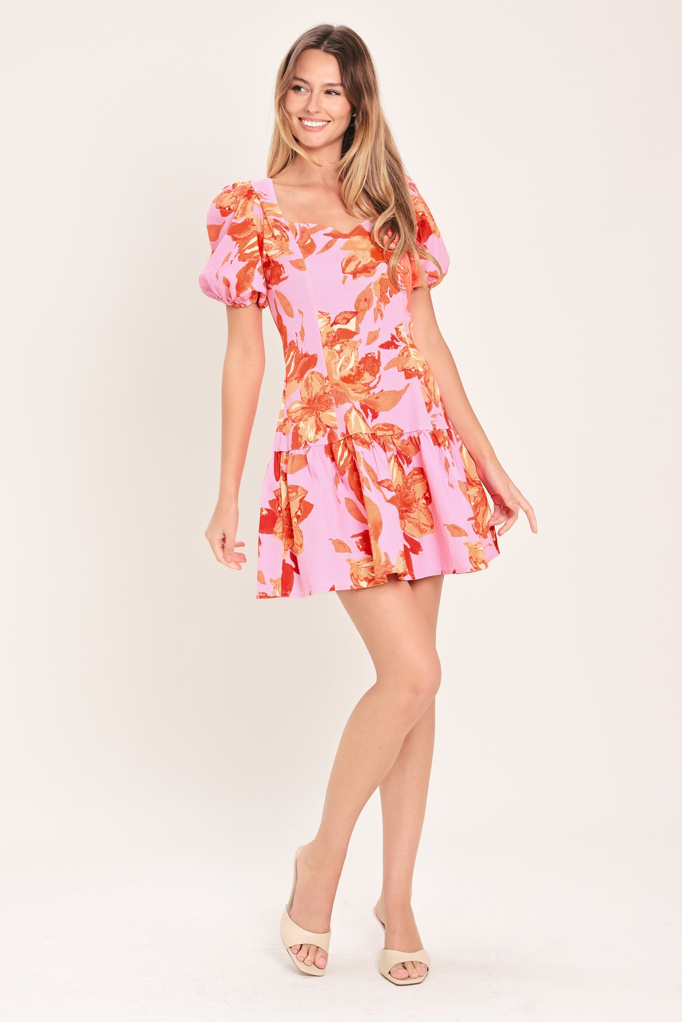 Woman wearing a lavender and coral floral printed mini dress featuring sweetheart neckline, short puff sleeve, ruffle hem and back zipper closure | Flying Tomato