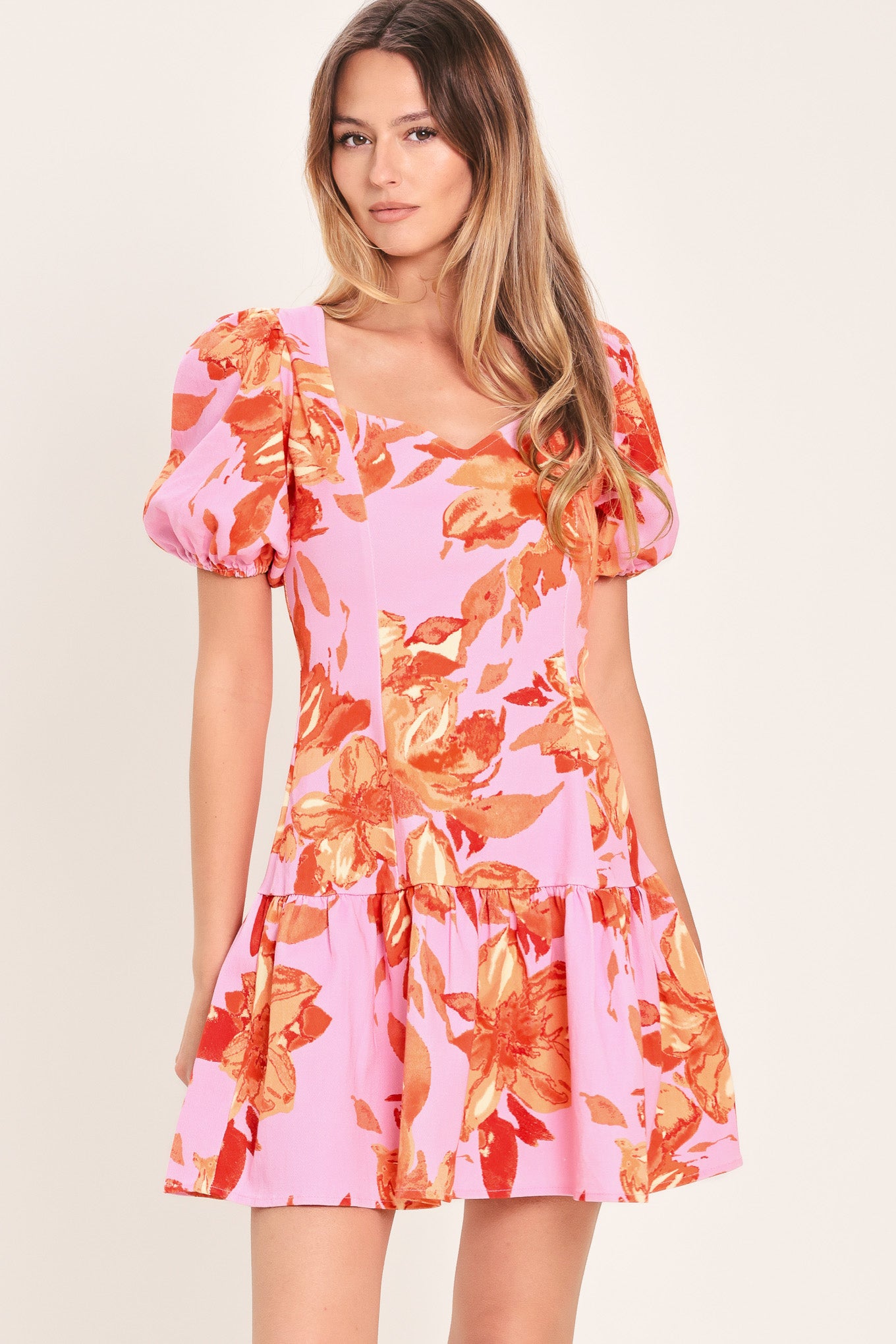 Woman wearing a lavender and coral floral printed mini dress featuring sweetheart neckline, short puff sleeve, ruffle hem and back zipper closure | Flying Tomato