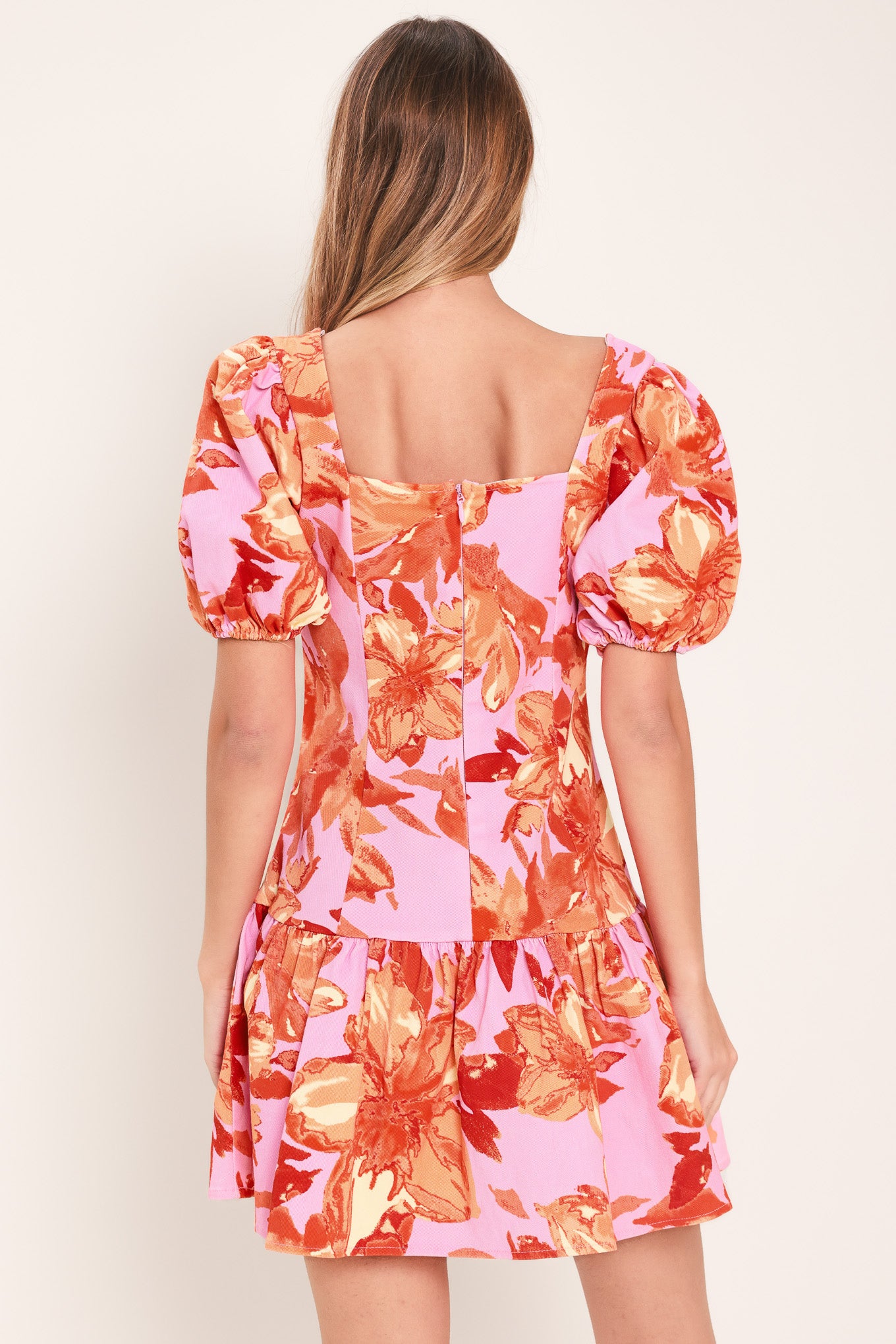 Woman wearing a lavender and coral floral printed mini dress featuring sweetheart neckline, short puff sleeve, ruffle hem and back zipper closure | Flying Tomato