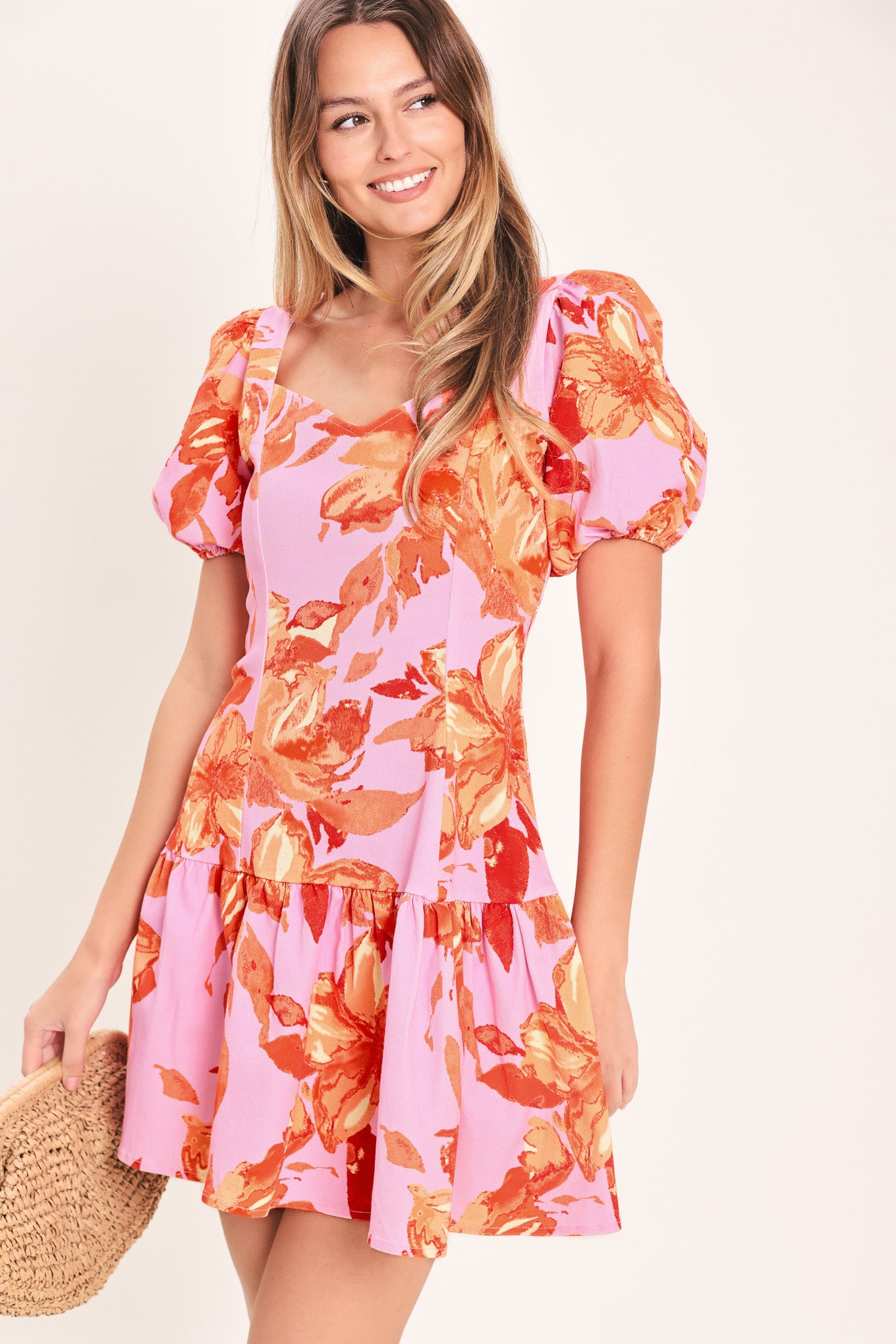 Woman wearing a lavender and coral floral printed mini dress featuring sweetheart neckline, short puff sleeve, ruffle hem and back zipper closure | Flying Tomato