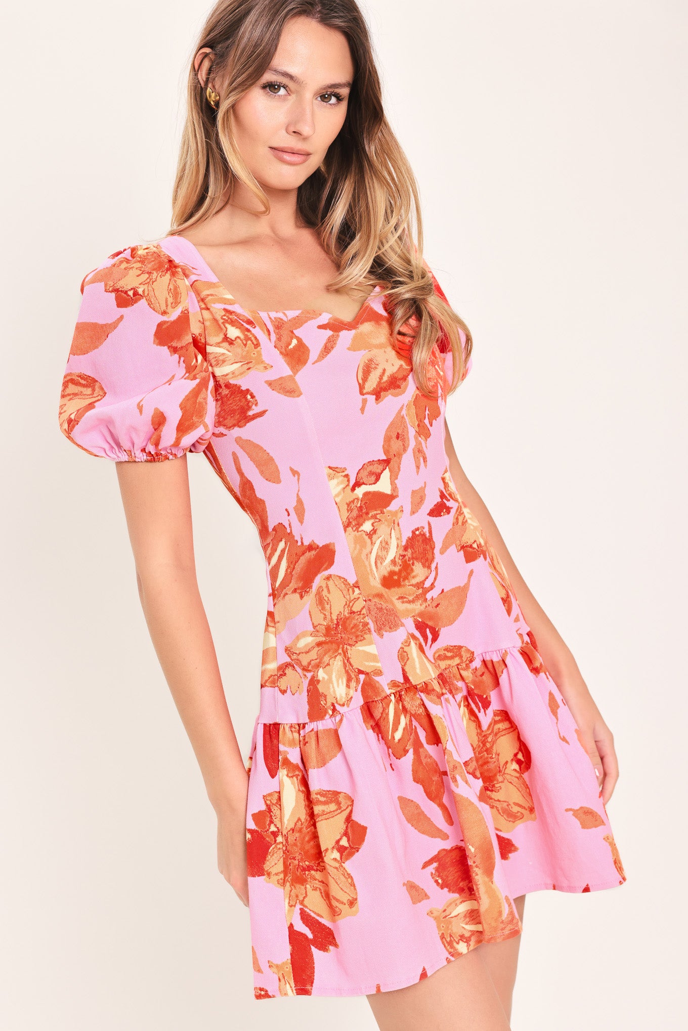 Woman wearing a lavender and coral floral printed mini dress featuring sweetheart neckline, short puff sleeve, ruffle hem and back zipper closure | Flying Tomato