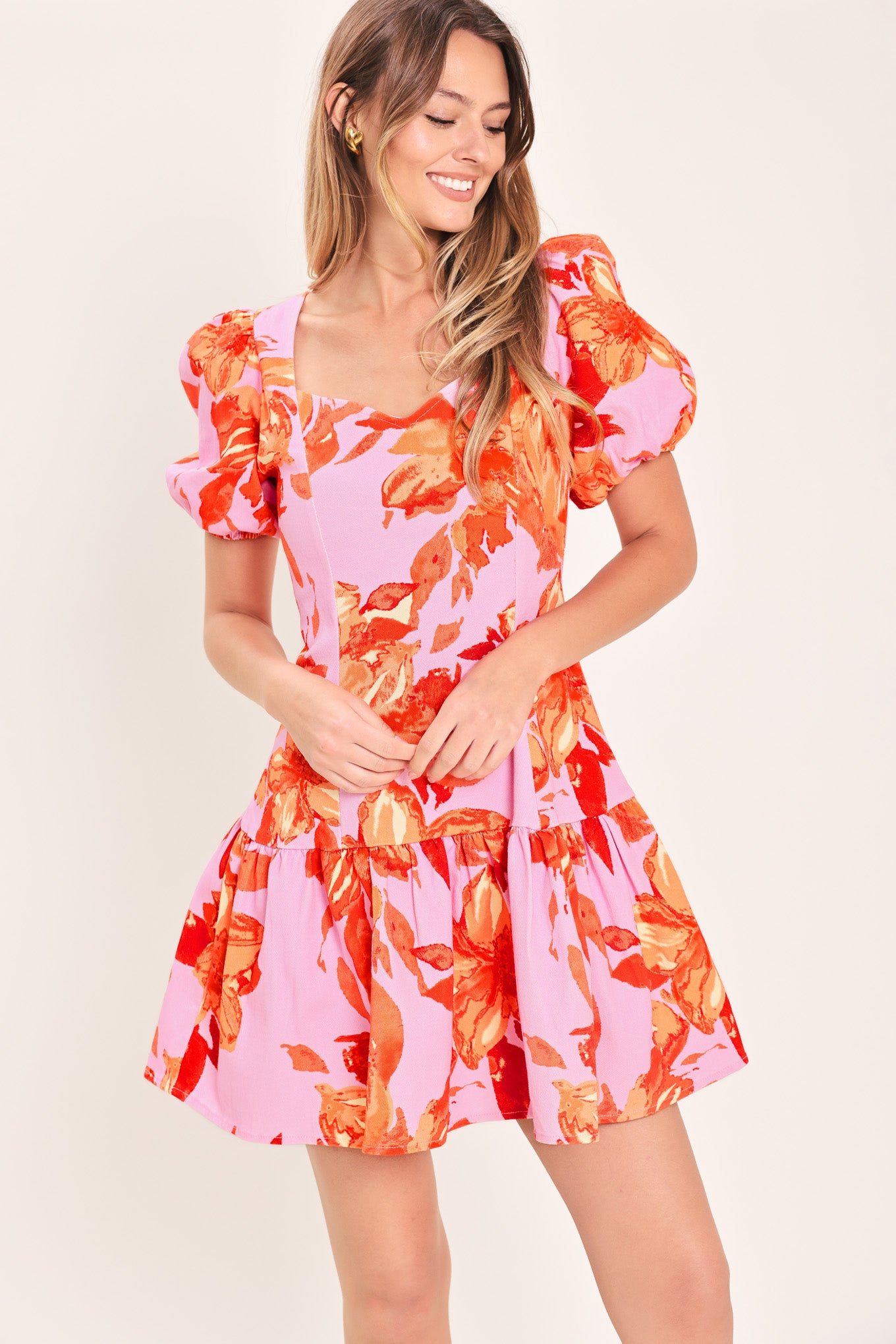 Woman wearing a lavender and coral floral printed mini dress featuring sweetheart neckline, short puff sleeve, ruffle hem and back zipper closure | Flying Tomato