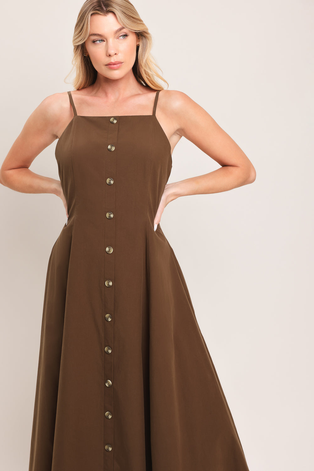 Woman wearing a brown midi dress featuring straight neckline, straps, front butt detail and back zipper closure | Flying Tomato
