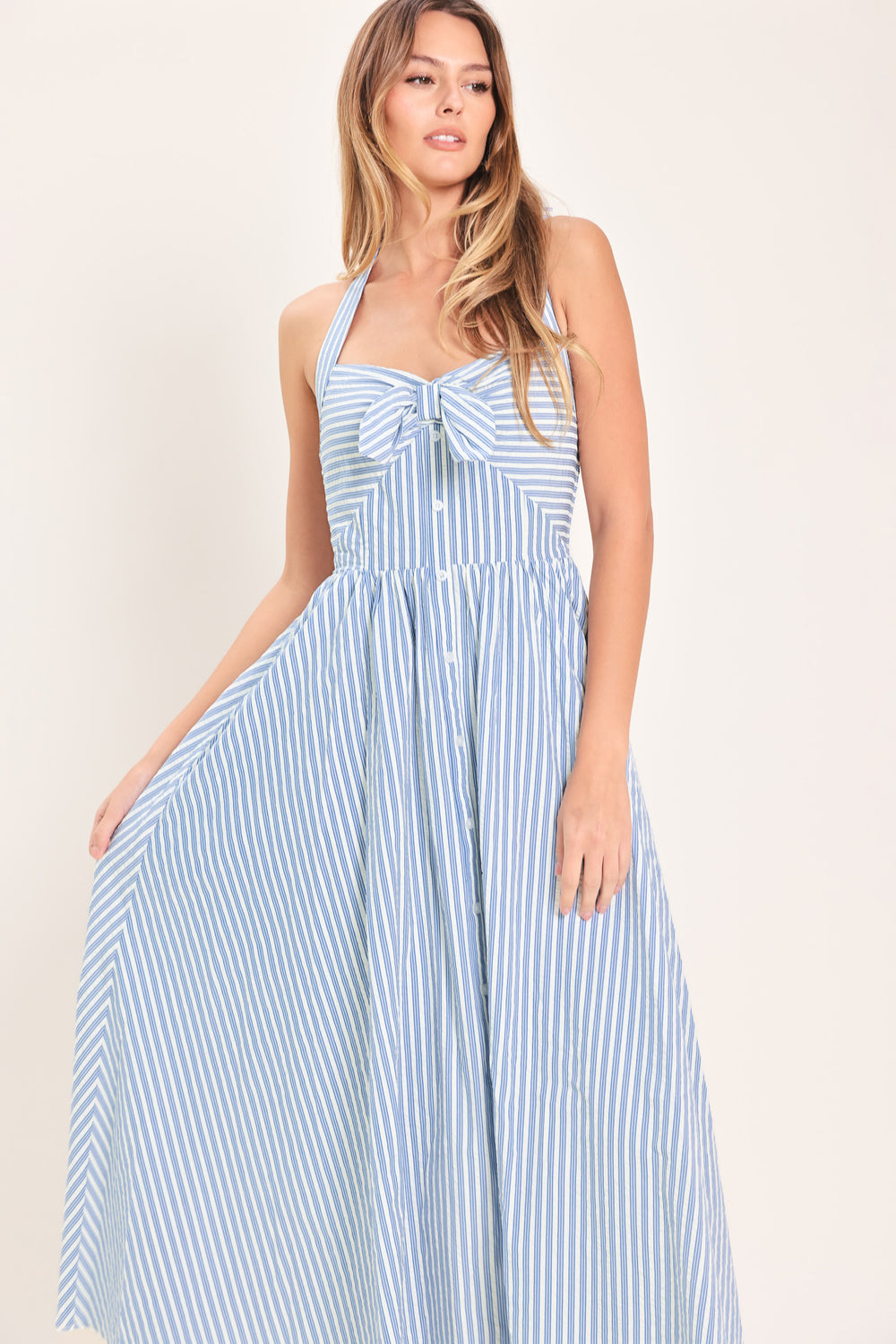 Woman wearing a striped woven midi dress featuring sweetheart halter neckline with back tie, front tie and button down, bare back with smocked back bodice | Flying Tomato