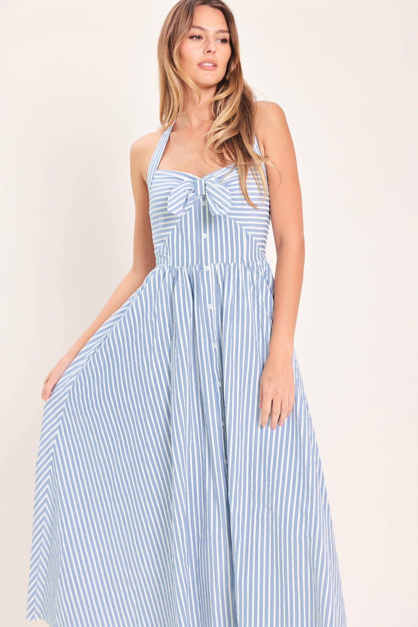 Woman wearing a striped woven midi dress featuring sweetheart halter neckline with back tie, front tie and button down, bare back with smocked back bodice | Flying Tomato
