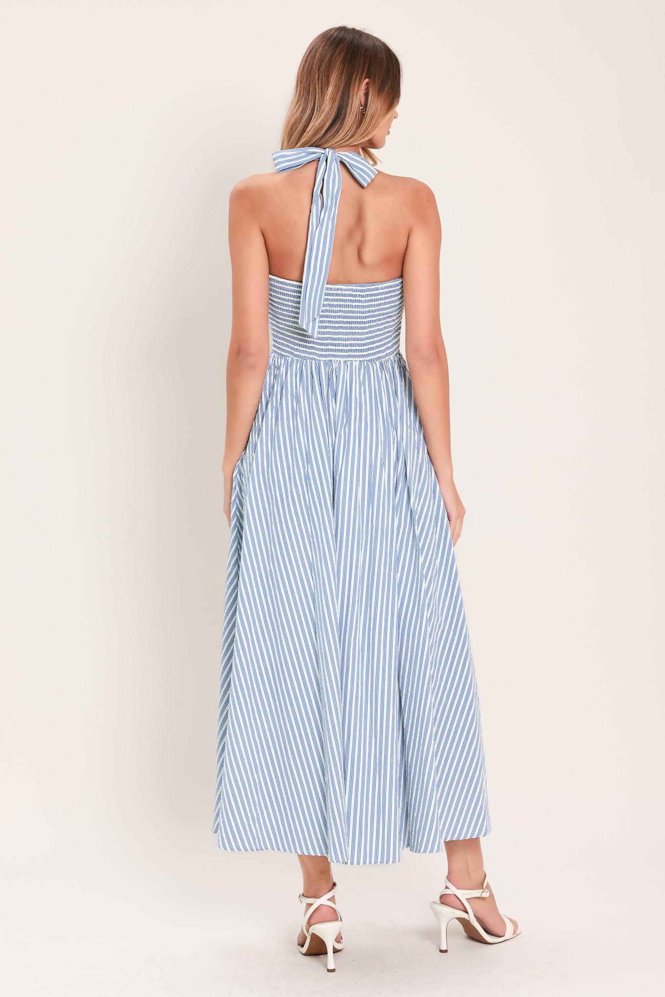 Woman wearing a striped woven midi dress featuring sweetheart halter neckline with back tie, front tie and button down, bare back with smocked back bodice | Flying Tomato