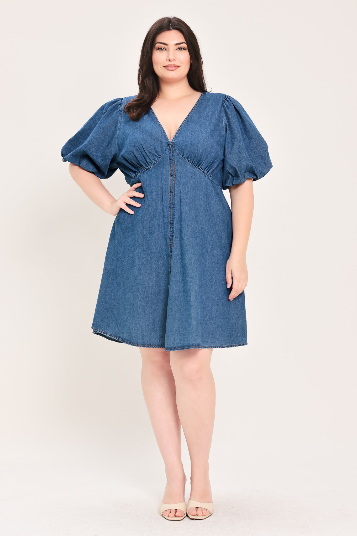 Woman wearing a denim mini dress featuring V neckline, short puff sleeve, button down detail, circle skirt and back zipper closure | Flying Tomato