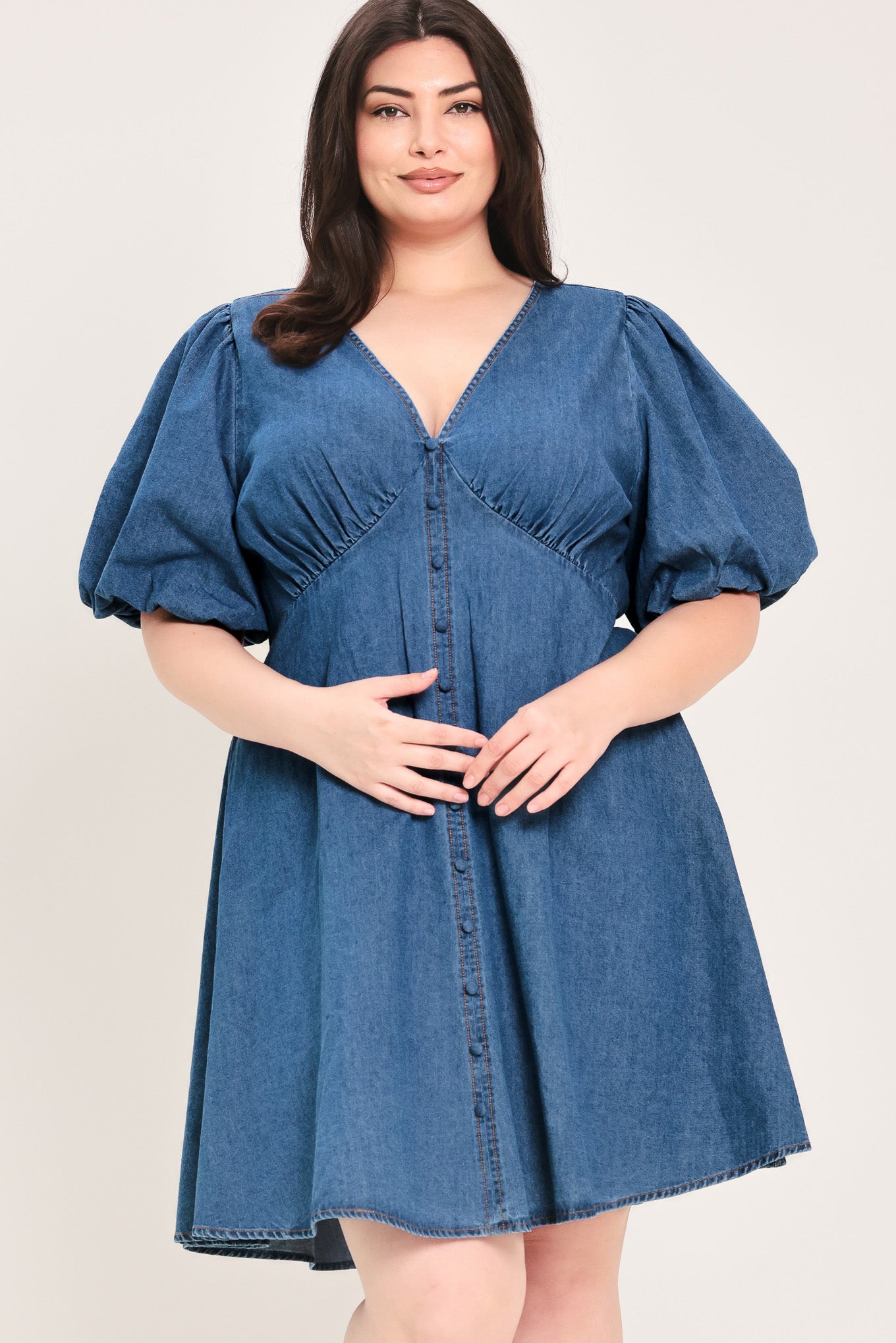 Woman wearing a denim mini dress featuring V neckline, short puff sleeve, button down detail, circle skirt and back zipper closure | Flying Tomato