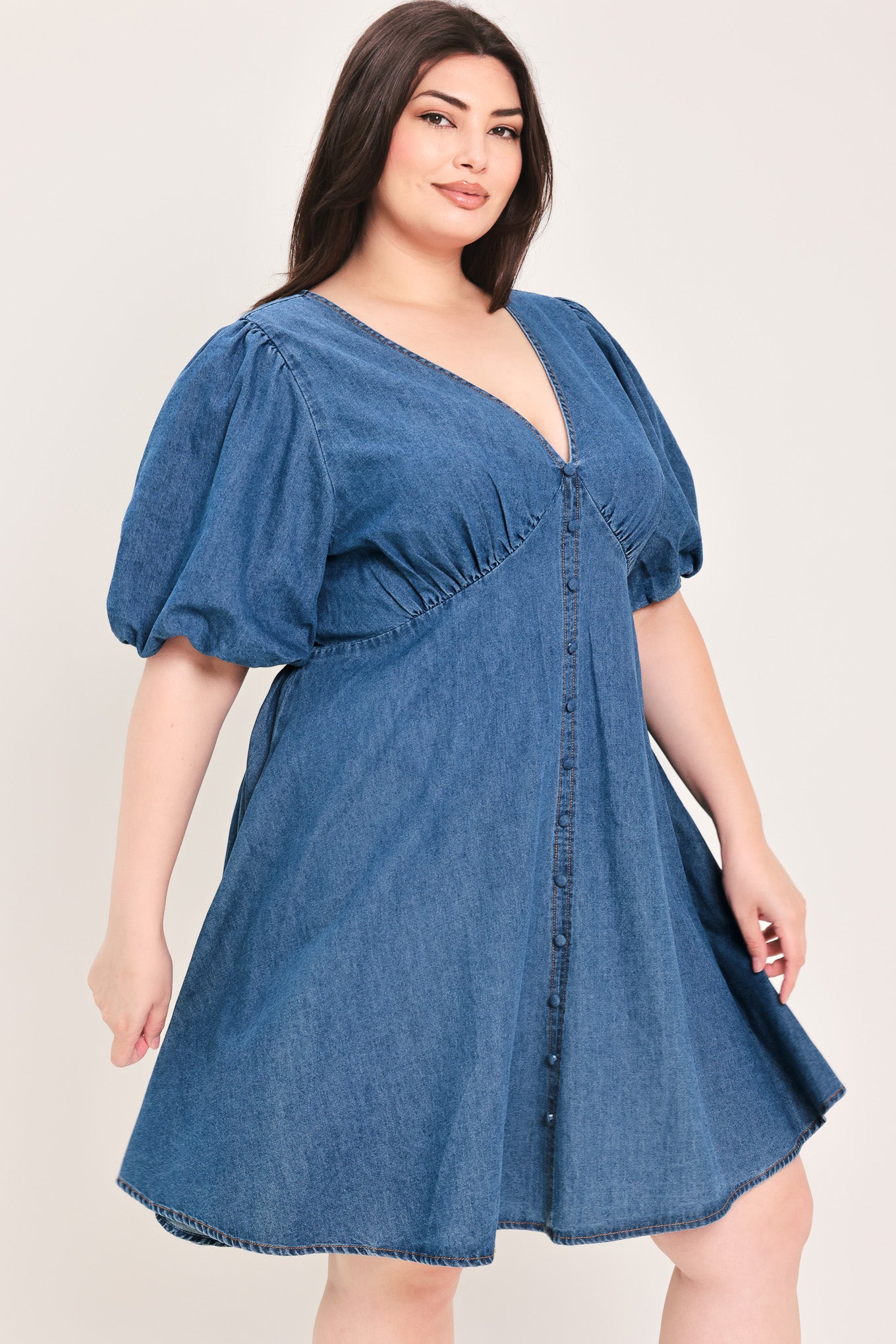 Woman wearing a denim mini dress featuring V neckline, short puff sleeve, button down detail, circle skirt and back zipper closure | Flying Tomato
