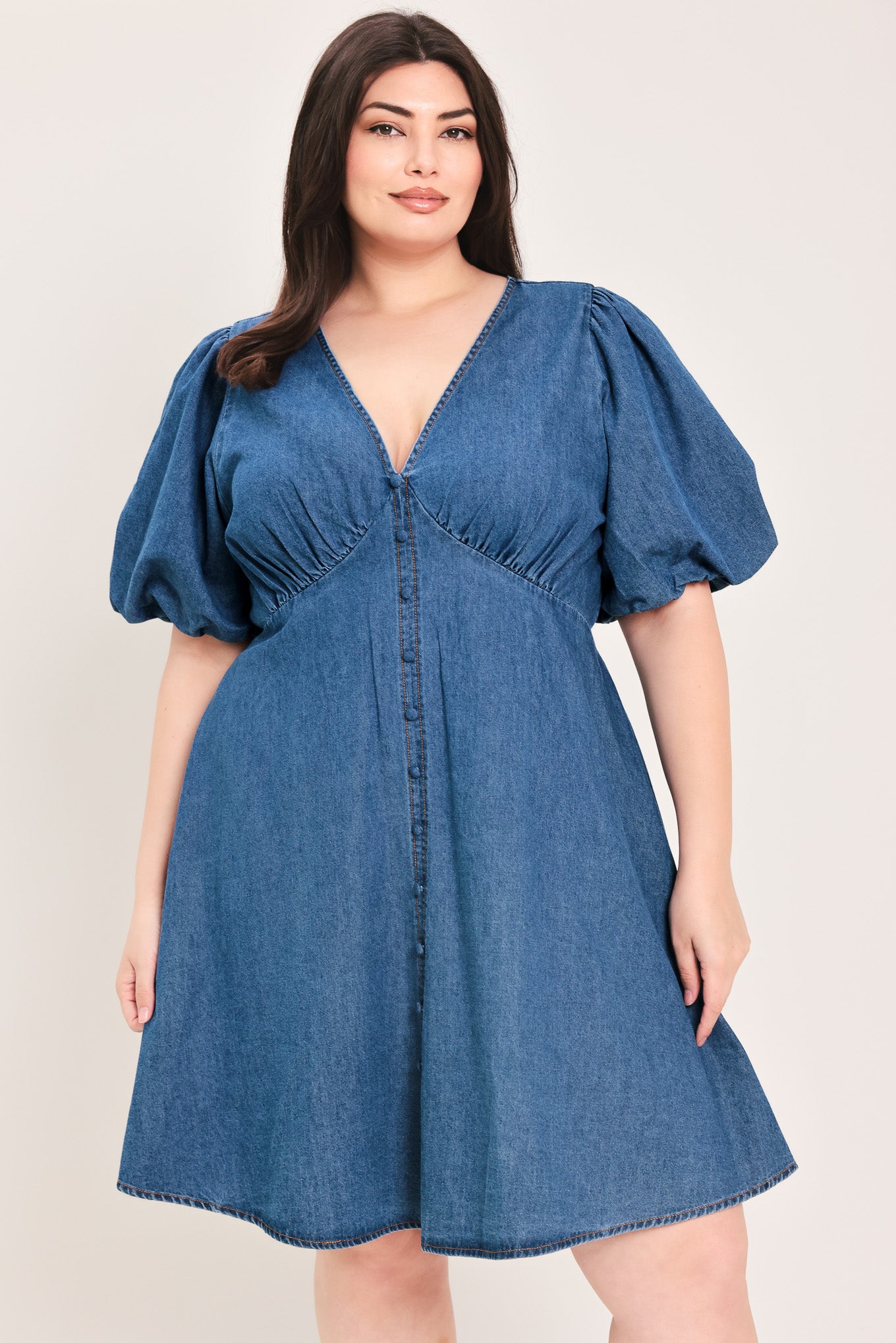 Woman wearing a denim mini dress featuring V neckline, short puff sleeve, button down detail, circle skirt and back zipper closure | Flying Tomato