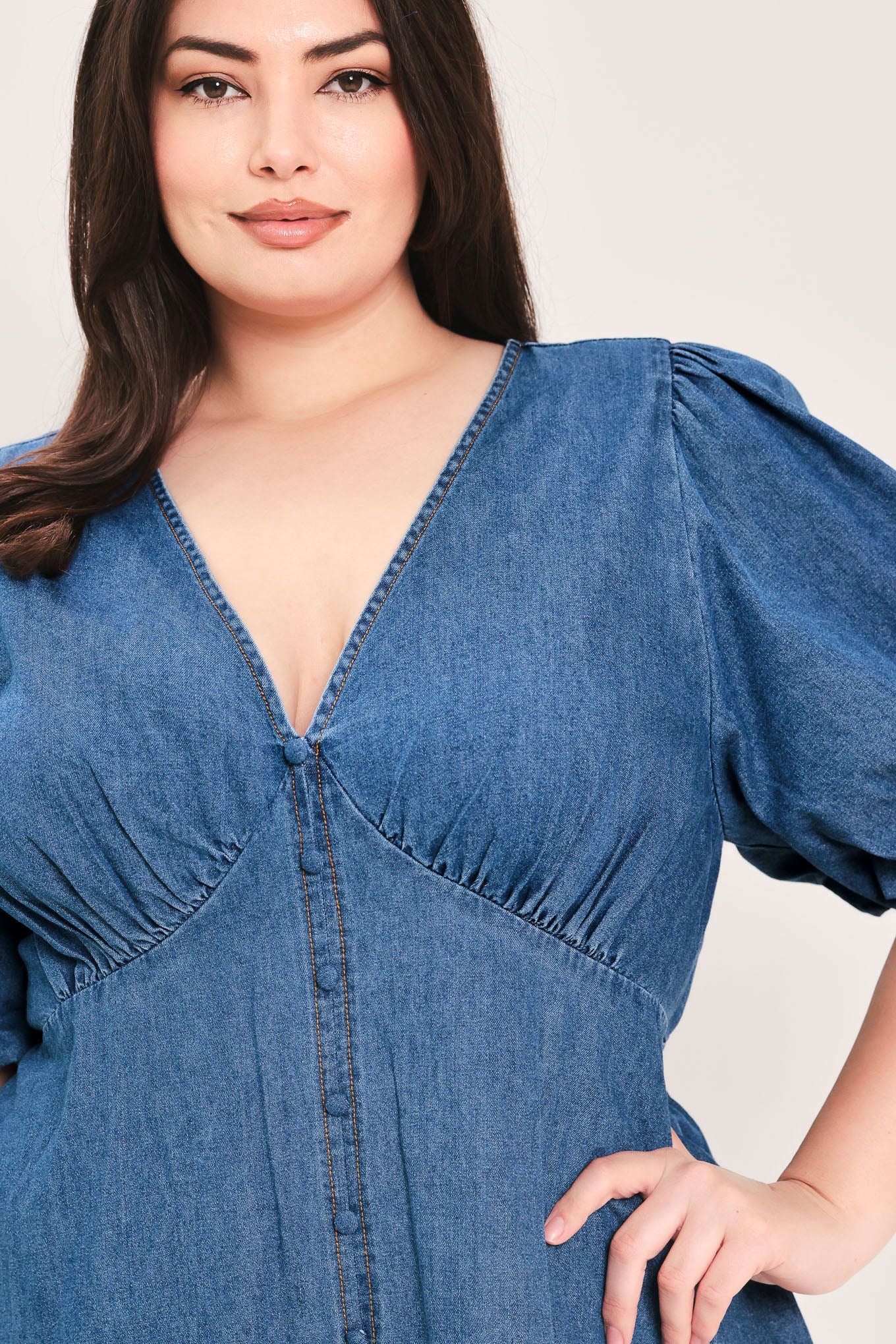Woman wearing a denim mini dress featuring V neckline, short puff sleeve, button down detail, circle skirt and back zipper closure | Flying Tomato