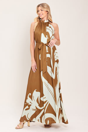 Woman wearing a brown maxi dress featuring halter neckline with back neck button closure, sleeveless and self sash tie | Flying Tomato