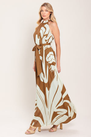 Woman wearing a brown maxi dress featuring halter neckline with back neck button closure, sleeveless and self sash tie | Flying Tomato