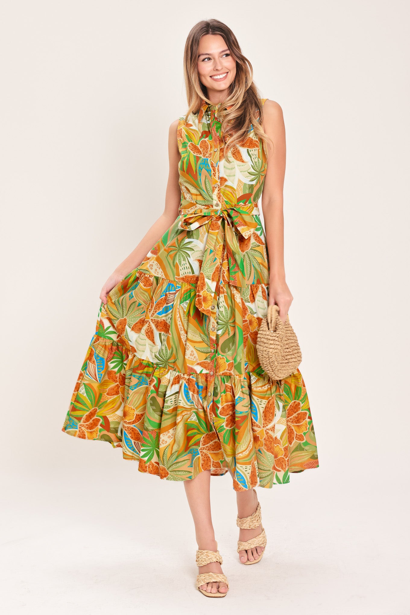 Woman wearing a rust and olive printed woven midi shirt dress featuring sleeveless, button down, self sash and tier skirt | Flying Tomato