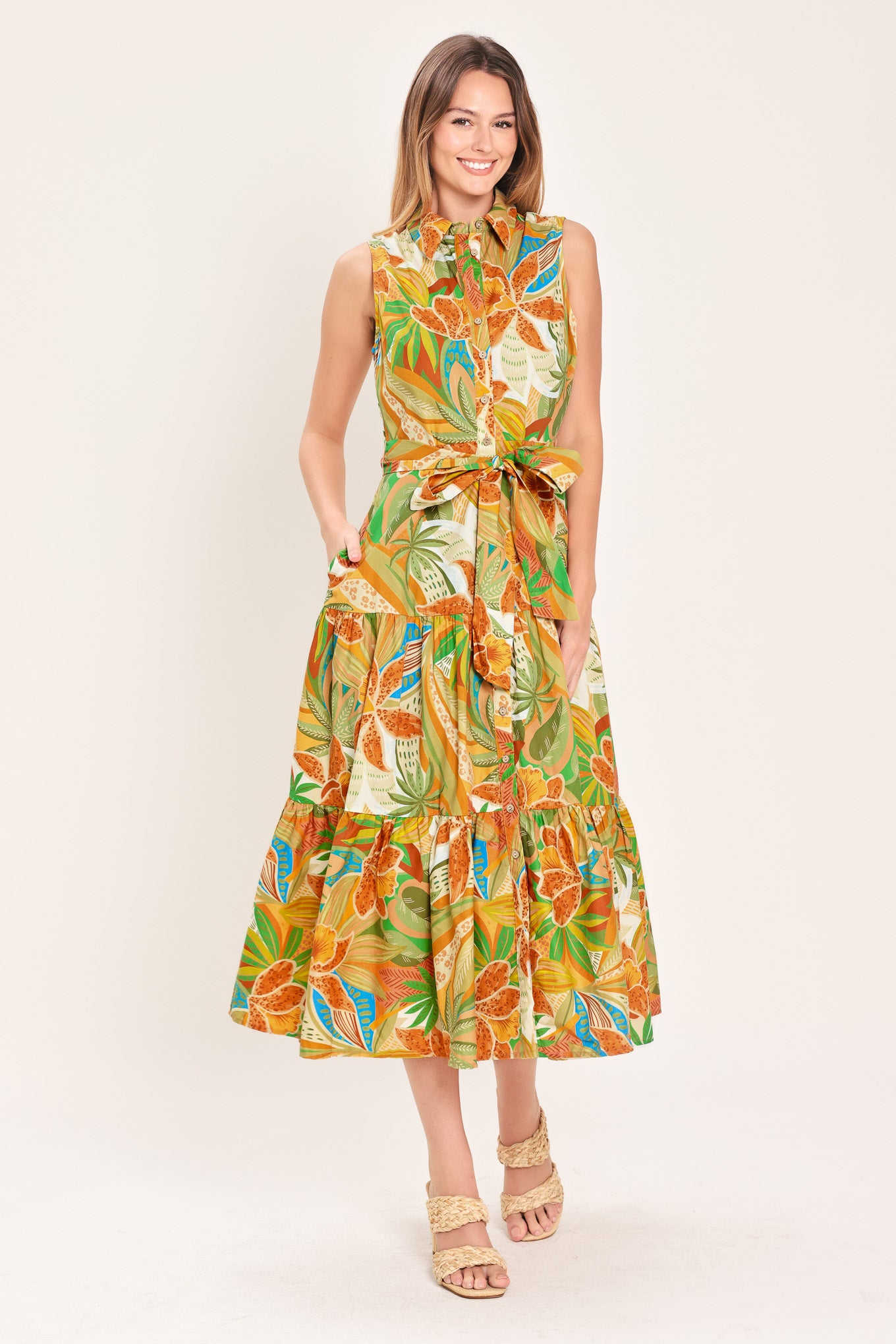 Woman wearing a rust and olive printed woven midi shirt dress featuring sleeveless, button down, self sash and tier skirt | Flying Tomato