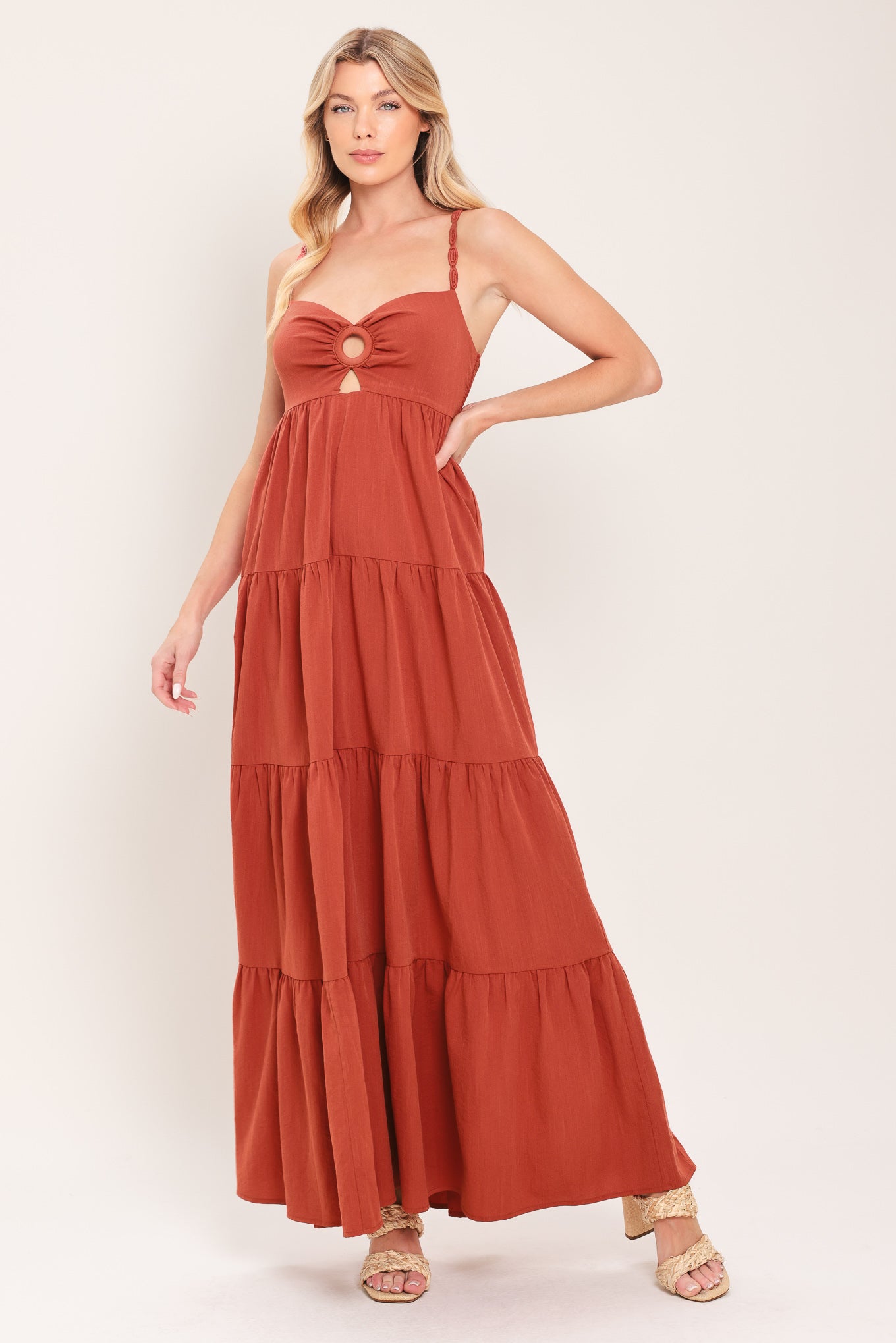 Woman wearing a rust-colored tiered maxi dress featuring cami top with O ring and cut out, lace straps, and smocked back bodice | Flying Tomato