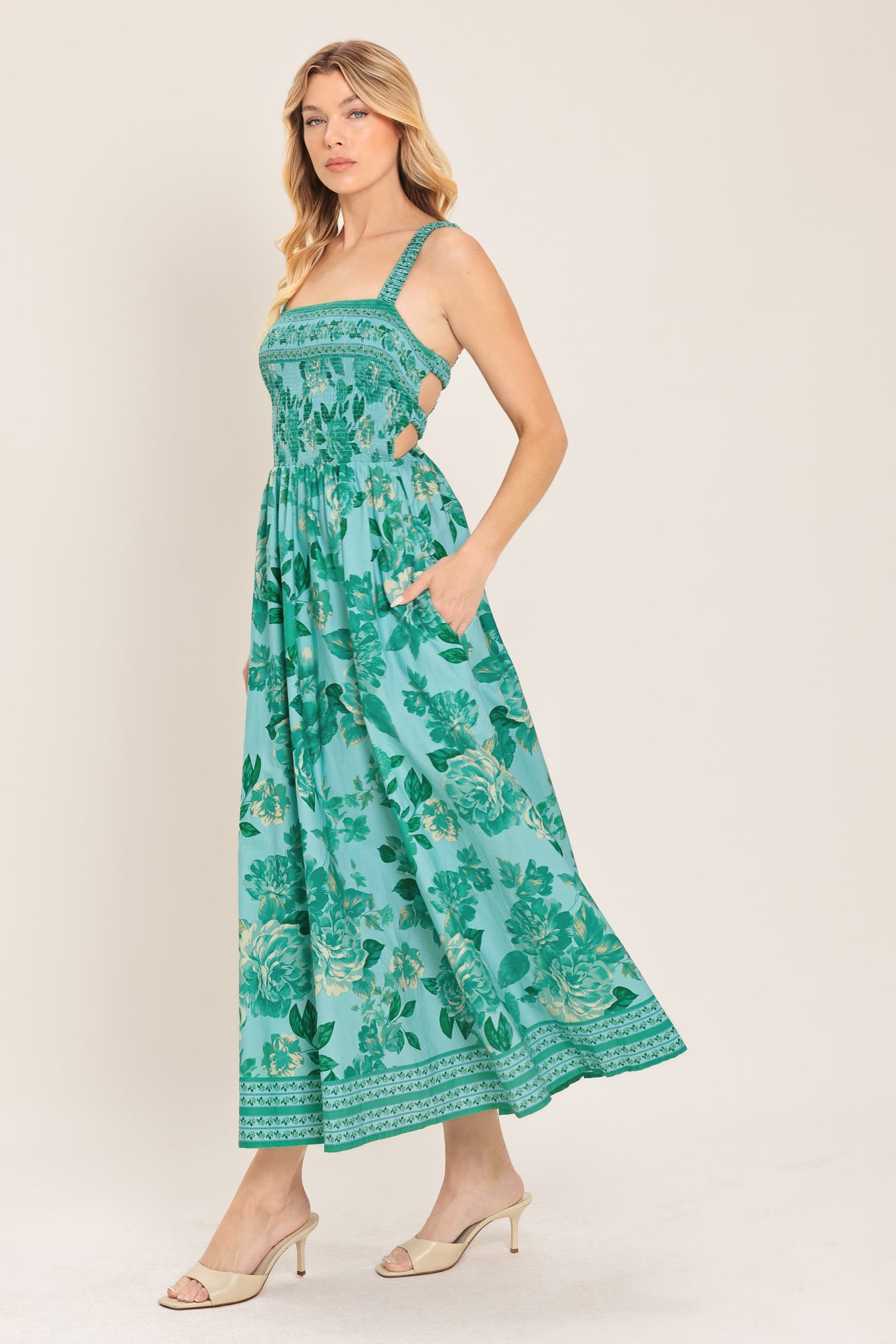 Woman wearing a teal floral midi dress featuring straight neckline with smocked bodice, full skirt and bare back with strap detail | Flying Tomato
