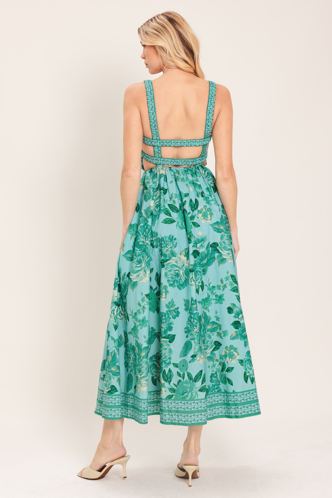 Woman wearing a teal floral midi dress featuring straight neckline with smocked bodice, full skirt and bare back with strap detail | Flying Tomato