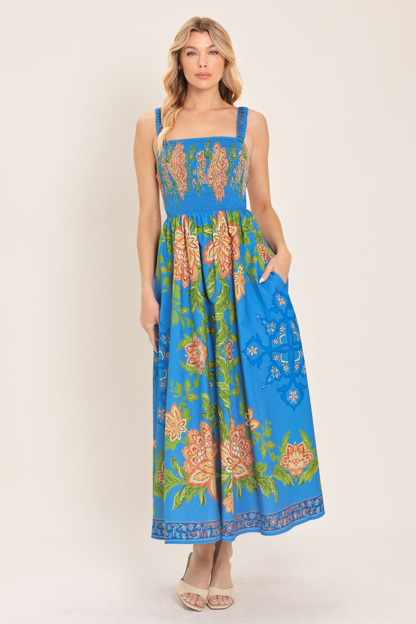 Woman wearing a blue floral midi dress with coral flowers and green leaves and geometric detail | Flying Tomato