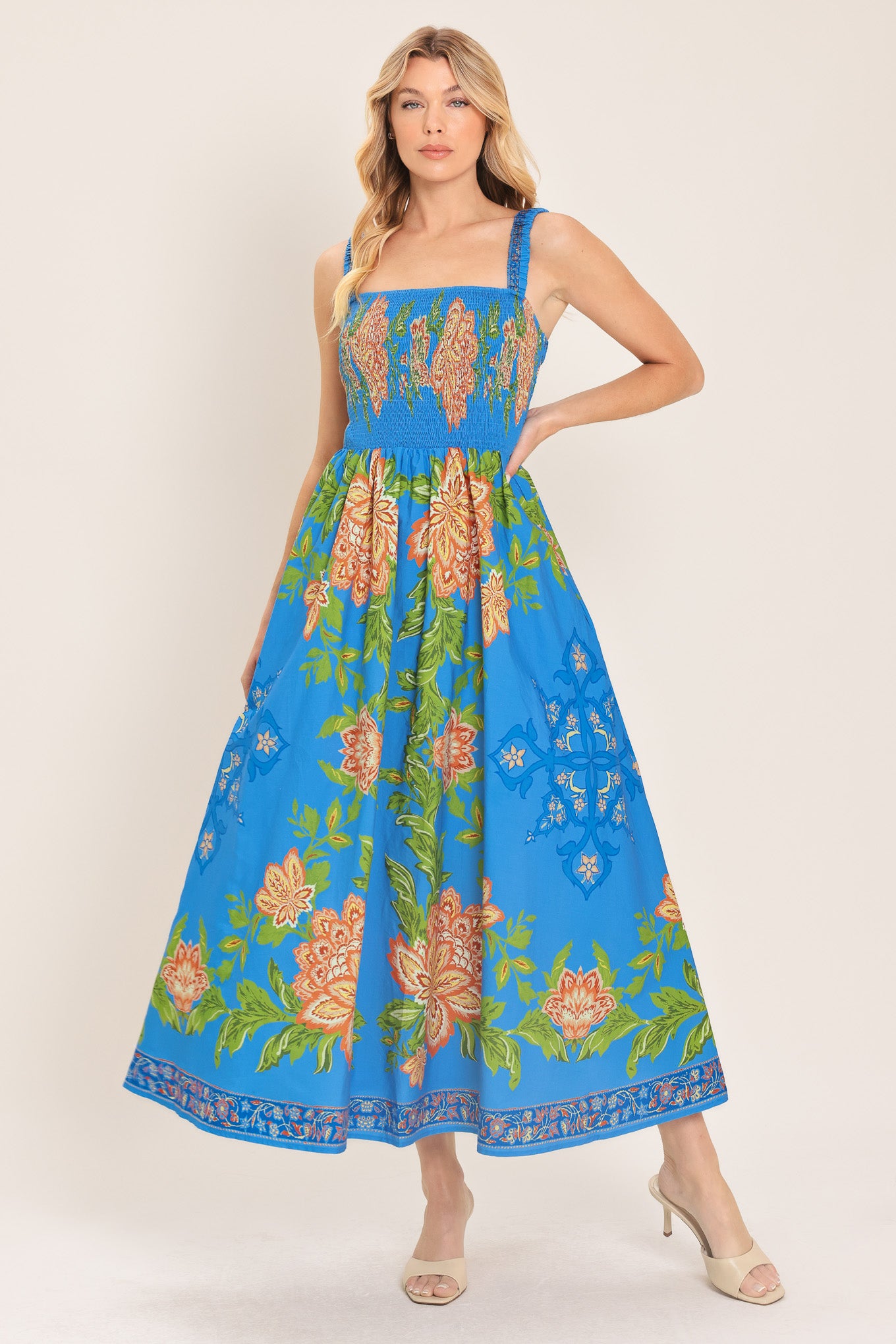 Woman wearing a blue floral midi dress with coral flowers and green leaves and geometric detail | Flying Tomato