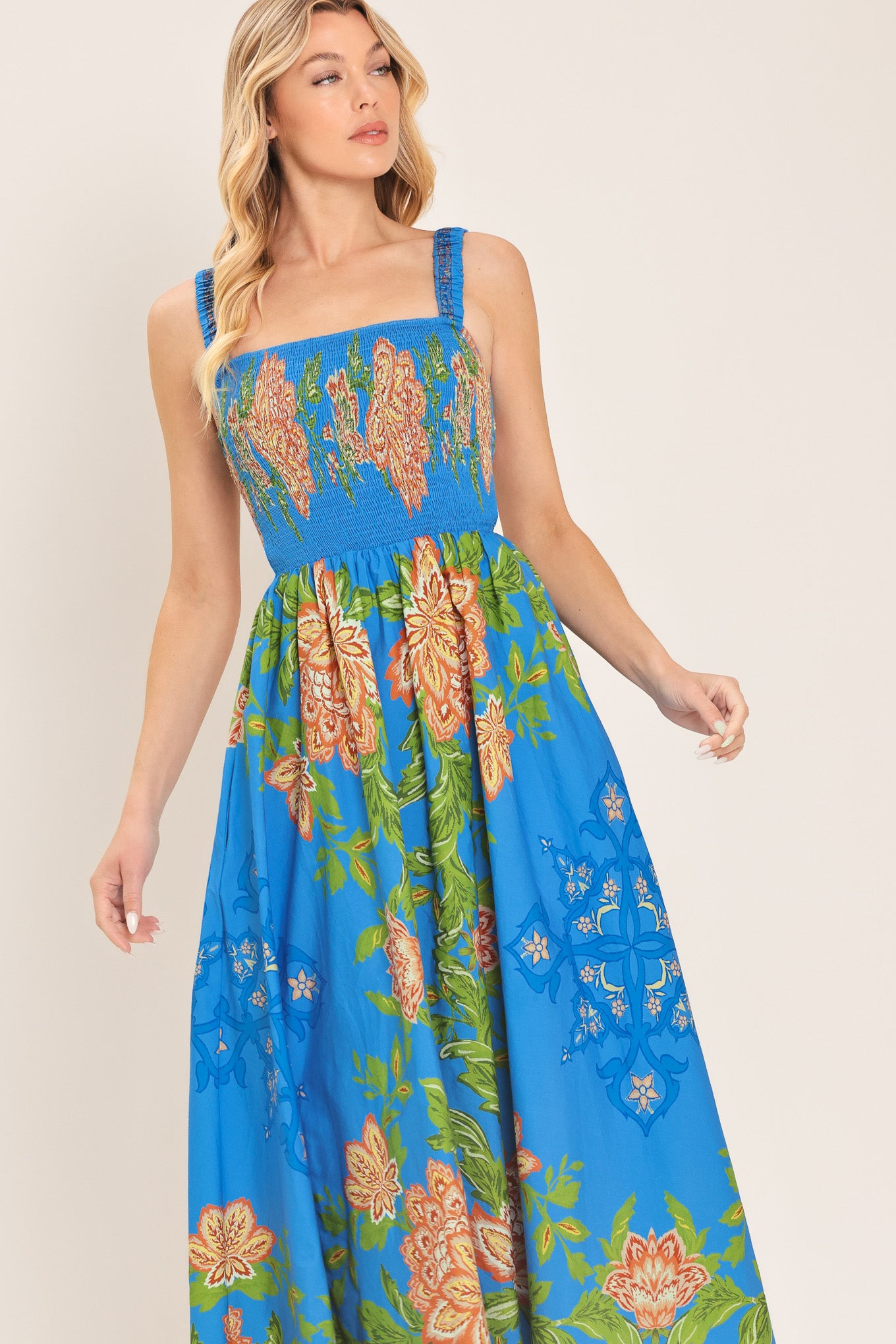 Woman wearing a blue floral midi dress with coral flowers and green leaves and geometric detail | Flying Tomato