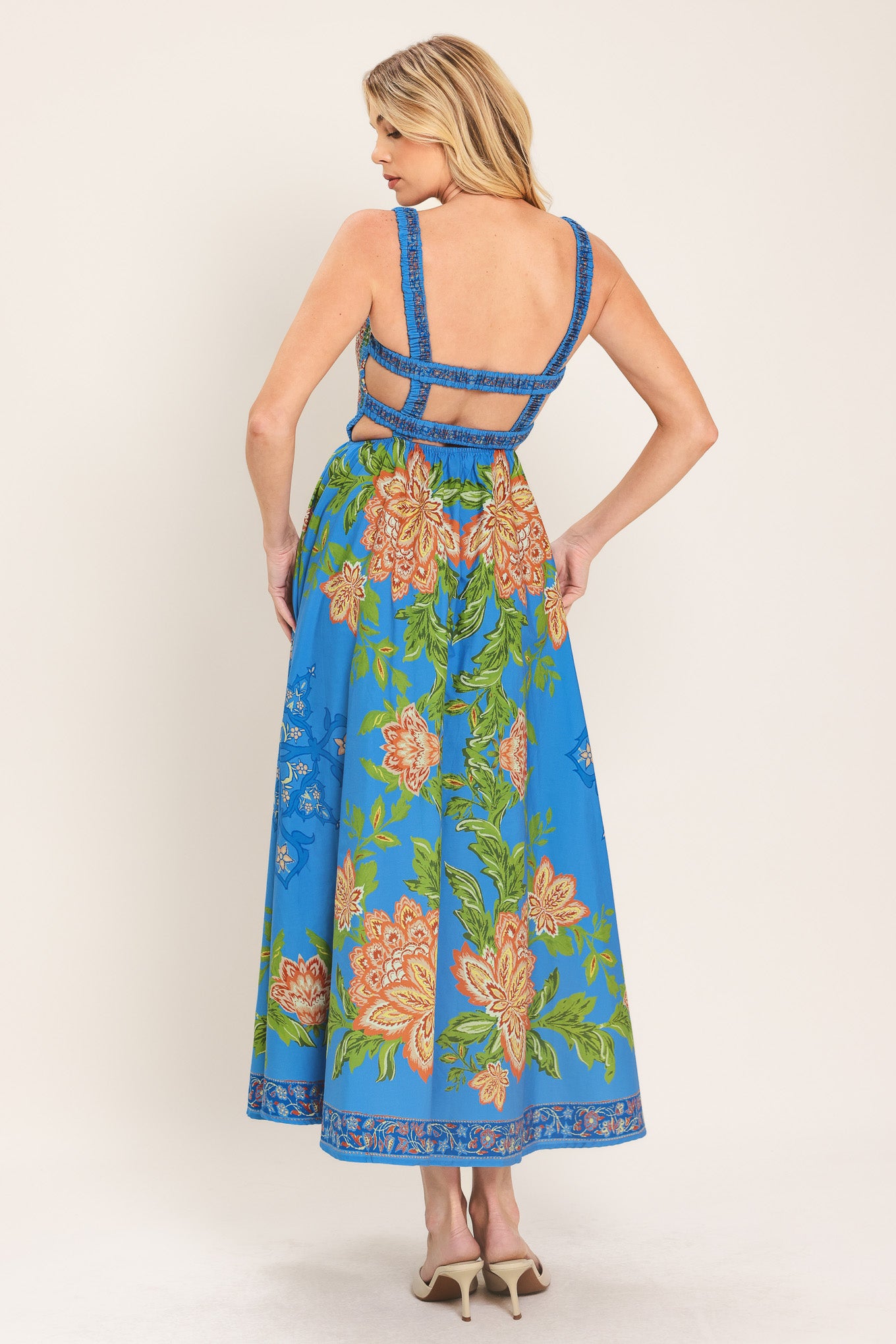 Woman wearing a blue floral midi dress with coral flowers and green leaves and geometric detail | Flying Tomato
