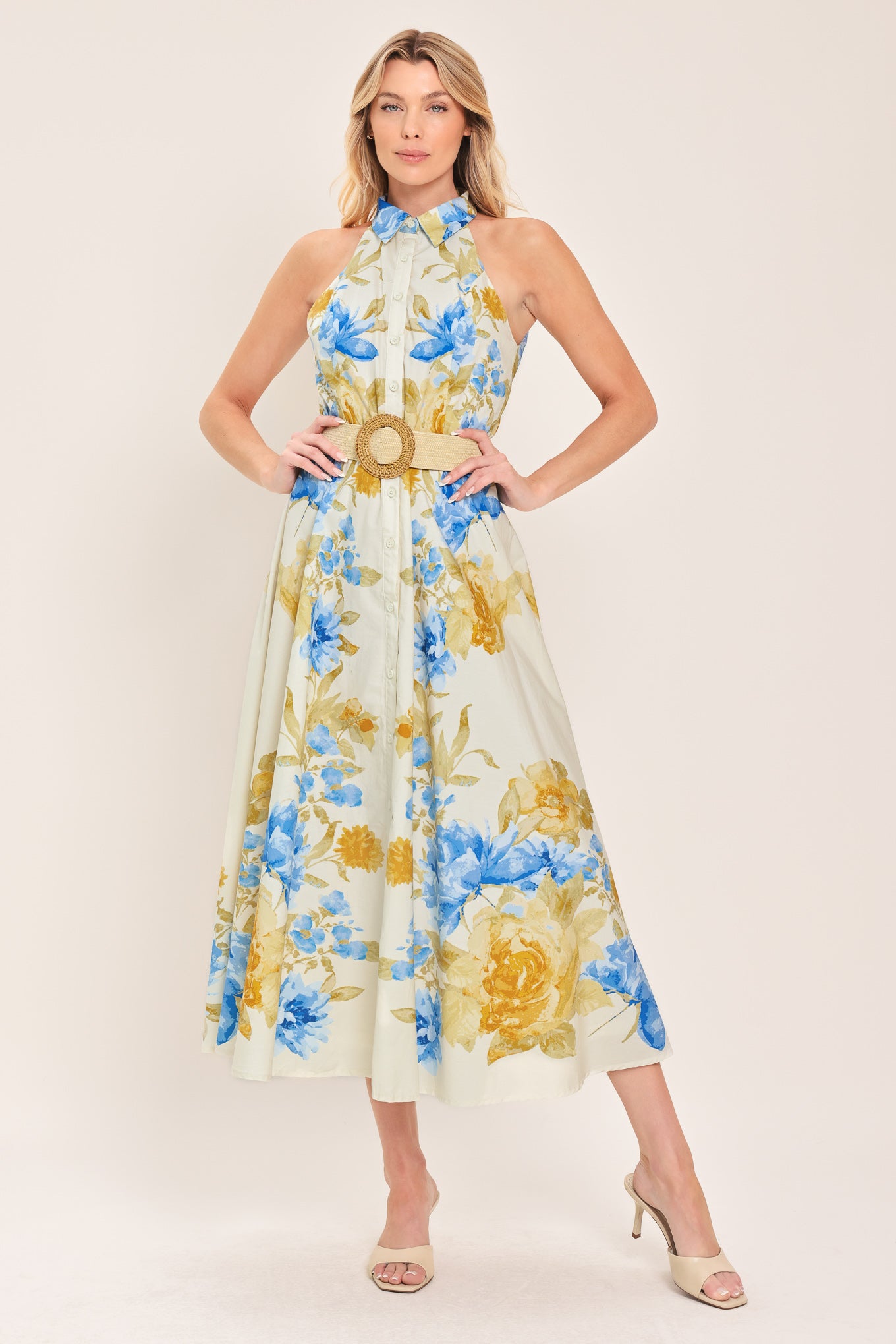 Woman wearing a sleeveless floral midi dress with blue and yellow flowers featuring a collar, front button closure and contrasting belt | Flying Tomato