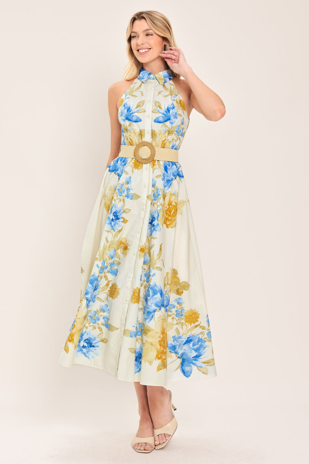 Woman wearing a sleeveless floral midi dress with blue and yellow flowers featuring a collar, front button closure and contrasting belt | Flying Tomato