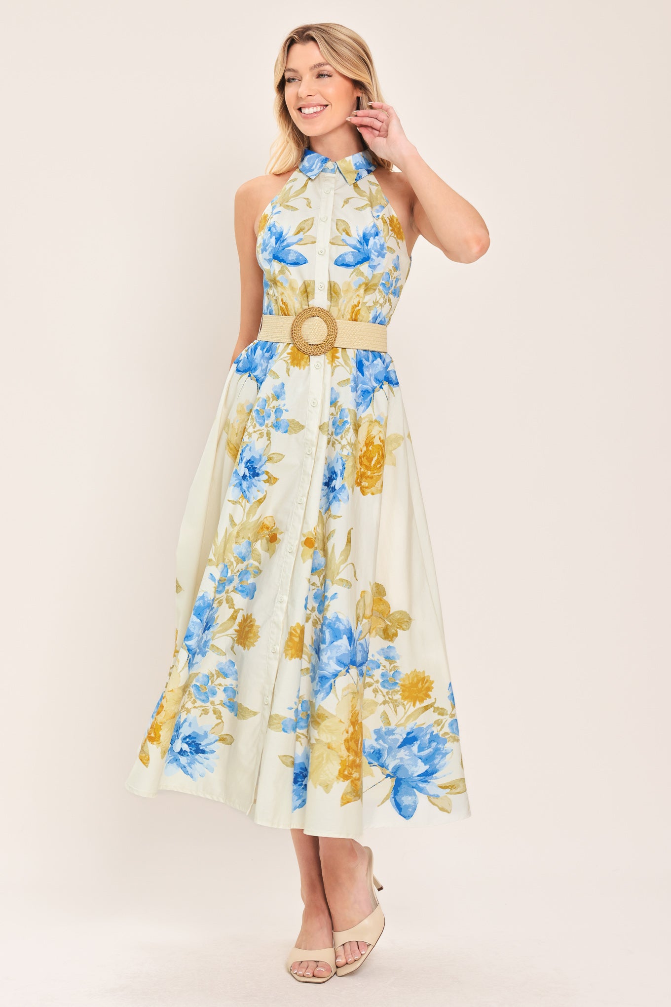 Woman wearing a sleeveless floral midi dress with blue and yellow flowers featuring a collar, front button closure and contrasting belt | Flying Tomato